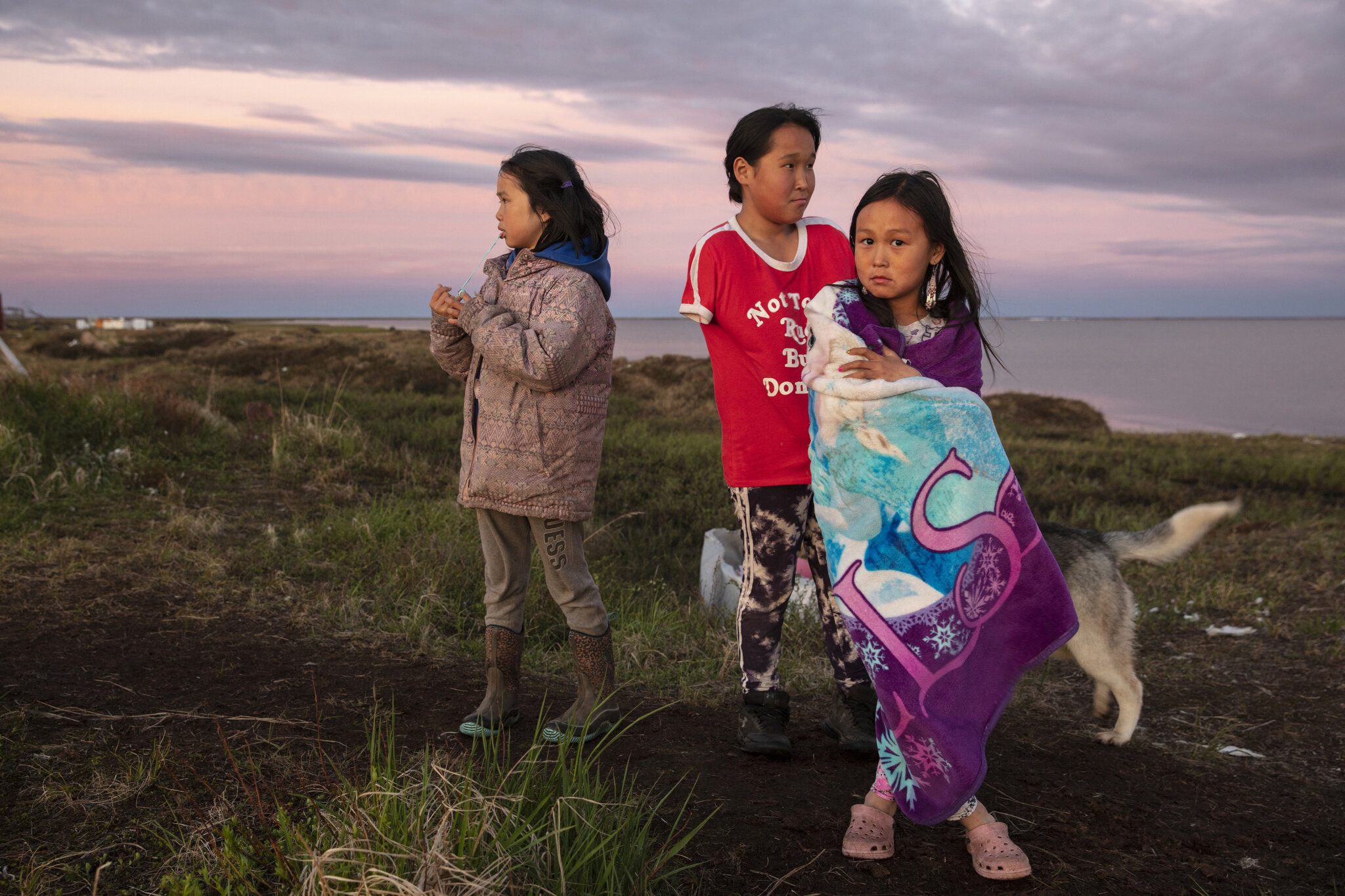  Children in Newtok, Alaska, play near crumbling permafrost cliffs that are now within a few dozen feet of numerous homes.  May 31st, 2019.The Yupik village of Newtok, Alaska, population 380, is sinking as the permafrost beneath it thaws and the coas