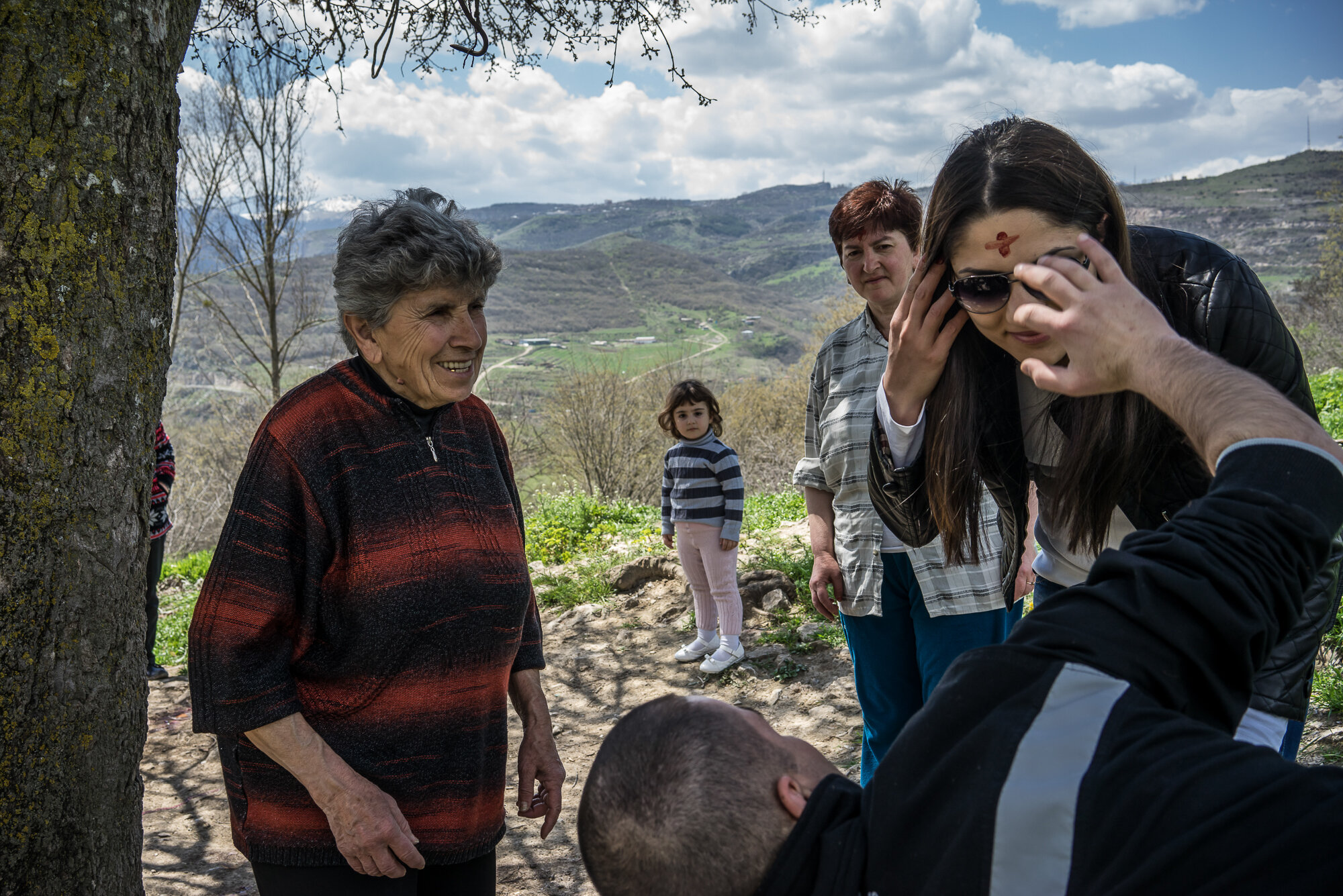  Members of the Abrahamyan family sacrifice a chicken, the blood of which is used to paint a cross on the forehead, to bring good fortune at the sacred site of Surb Saribek. Karashen, Nagorno-Karabakh. 2015. 