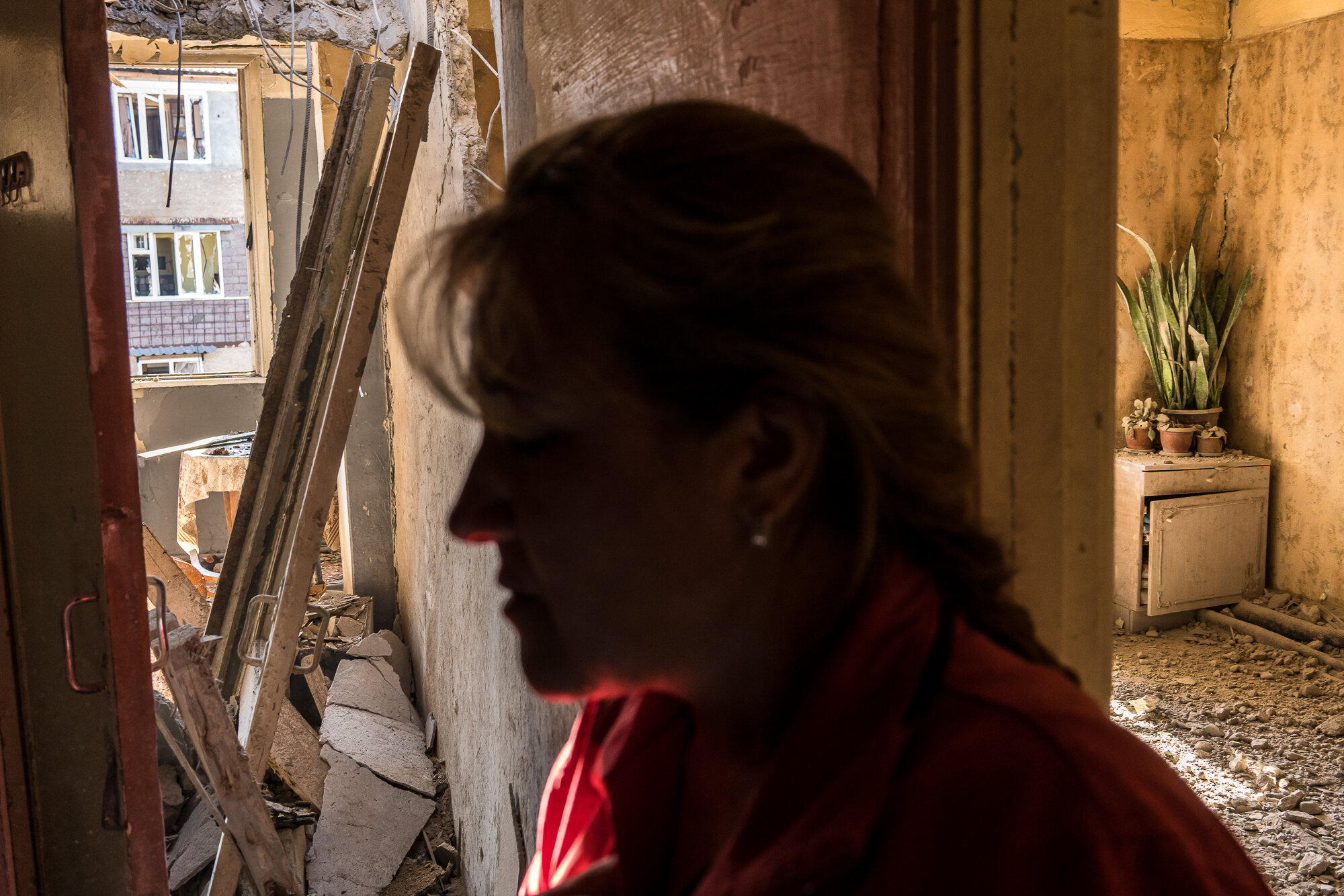  Alina Shumanyan reacts to the destruction in her neighbor's apartment building after it was shelled the previous evening. Stepanakert, Nagorno-Karabakh. 2020. 