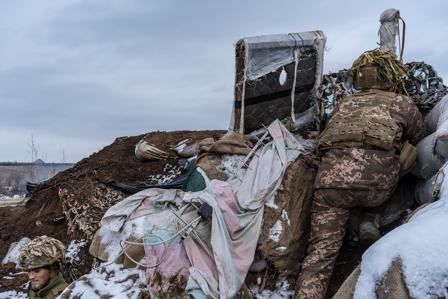  Pavlo (R), a Ukrainian soldier, uses a small hand-held periscope to view the positions of Russian-backed troops from a small bunker near on the front line on January 17, 2022 in the village of New York, formerly known as Novhorodske, Ukraine. 