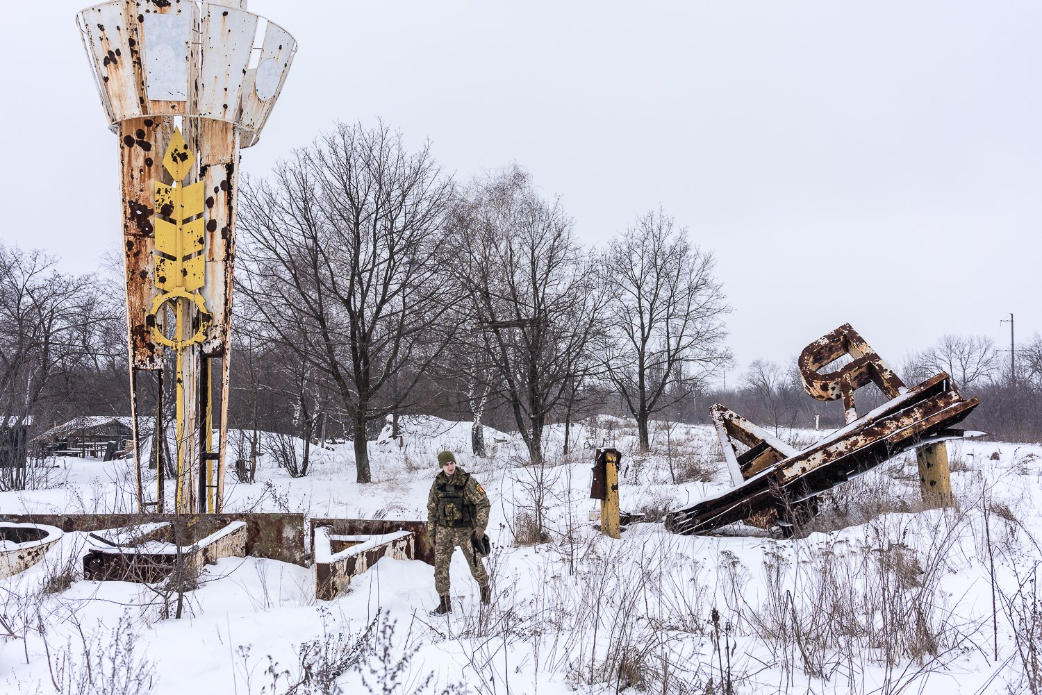  A Ukrainian soldier with the 24th brigade walks near a destroyed sign at the entrance to the front-line city on Monday, January 24, 2022 in Popasna, Ukraine. 