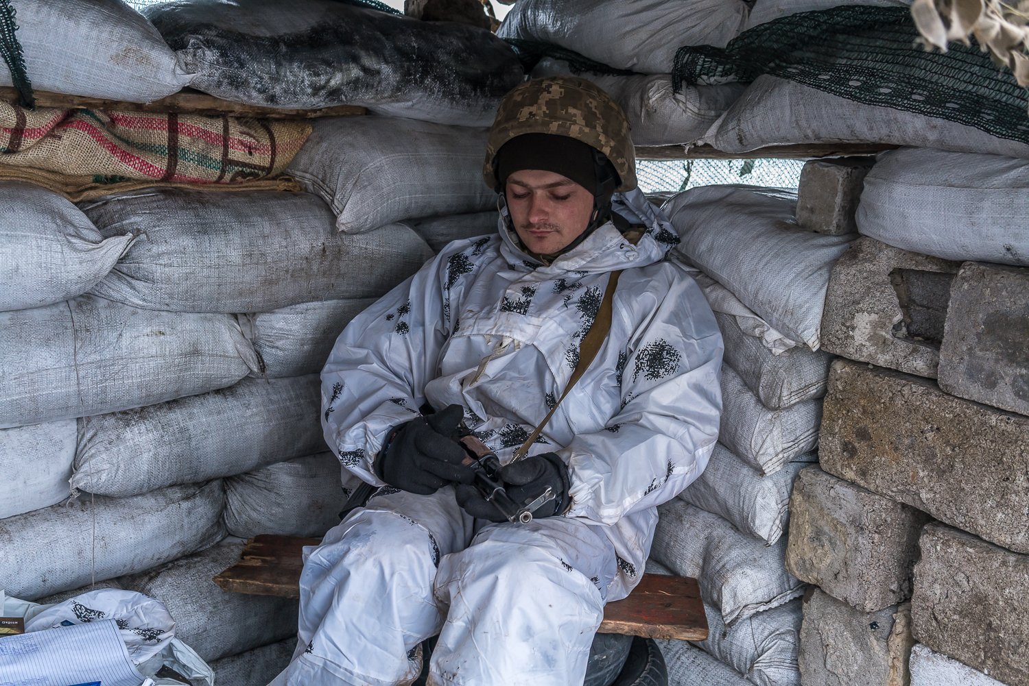  Andriy, a Ukrainian soldier with the 53rd Mechanized Brigade, sits in a small shelter at a checkpoint on the road into town on Saturday, January 29, 2022 in Chermalyk, Ukraine. 