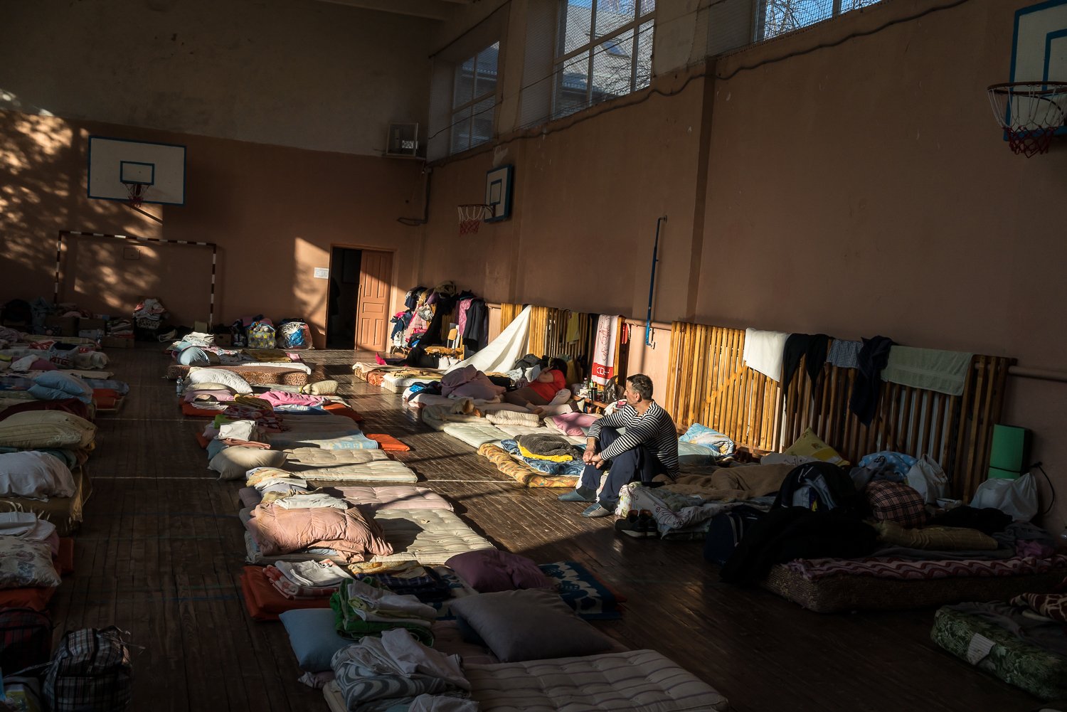  A man sits inside a gymnasium at School Number 1 that has been converted to a facility to house people displaced by the Russian invasion on Sunday, March 13, 2022 in Novoyavorivsk, Ukraine. 