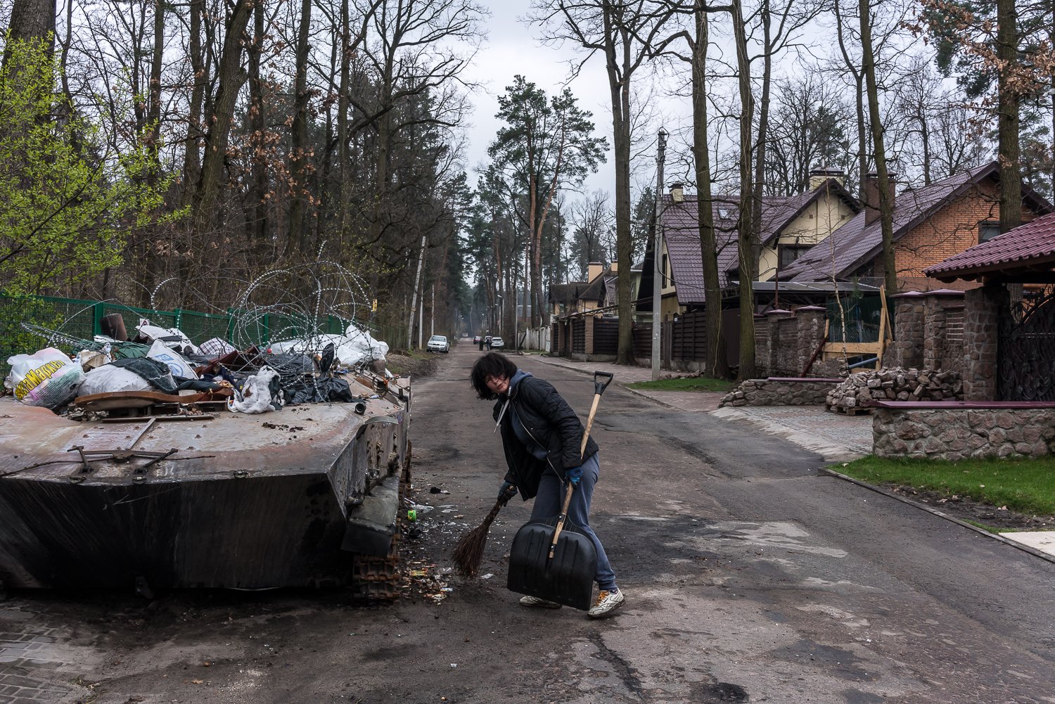  A woman who gave her name only as Nadiya sweeps up around a destroyed Russian armored personnel carrier that has been converted into a dumpster on Thursday, April 21, 2022 in Irpin, Ukraine. 