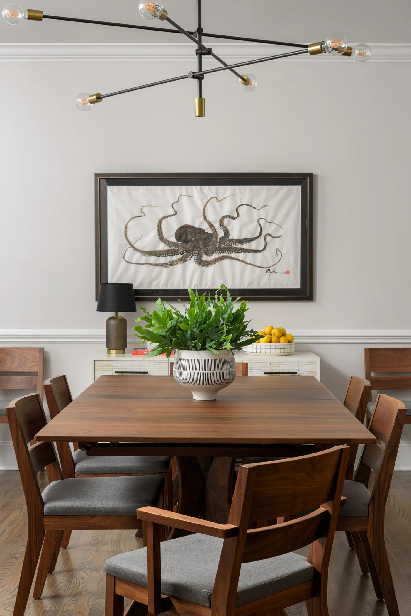 A sculptural mid-century inspired chandelier floats above a walnut dining table and chairs.
