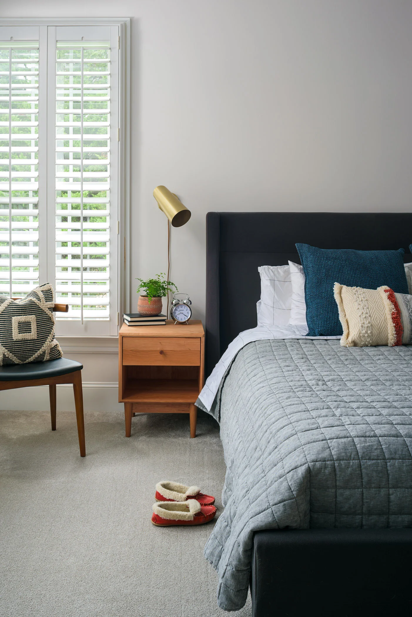 A bright and airy master bedroom. Gray walls bounce lots of light around while natural woods, soft textiles, and a pop of brass warm up the room.