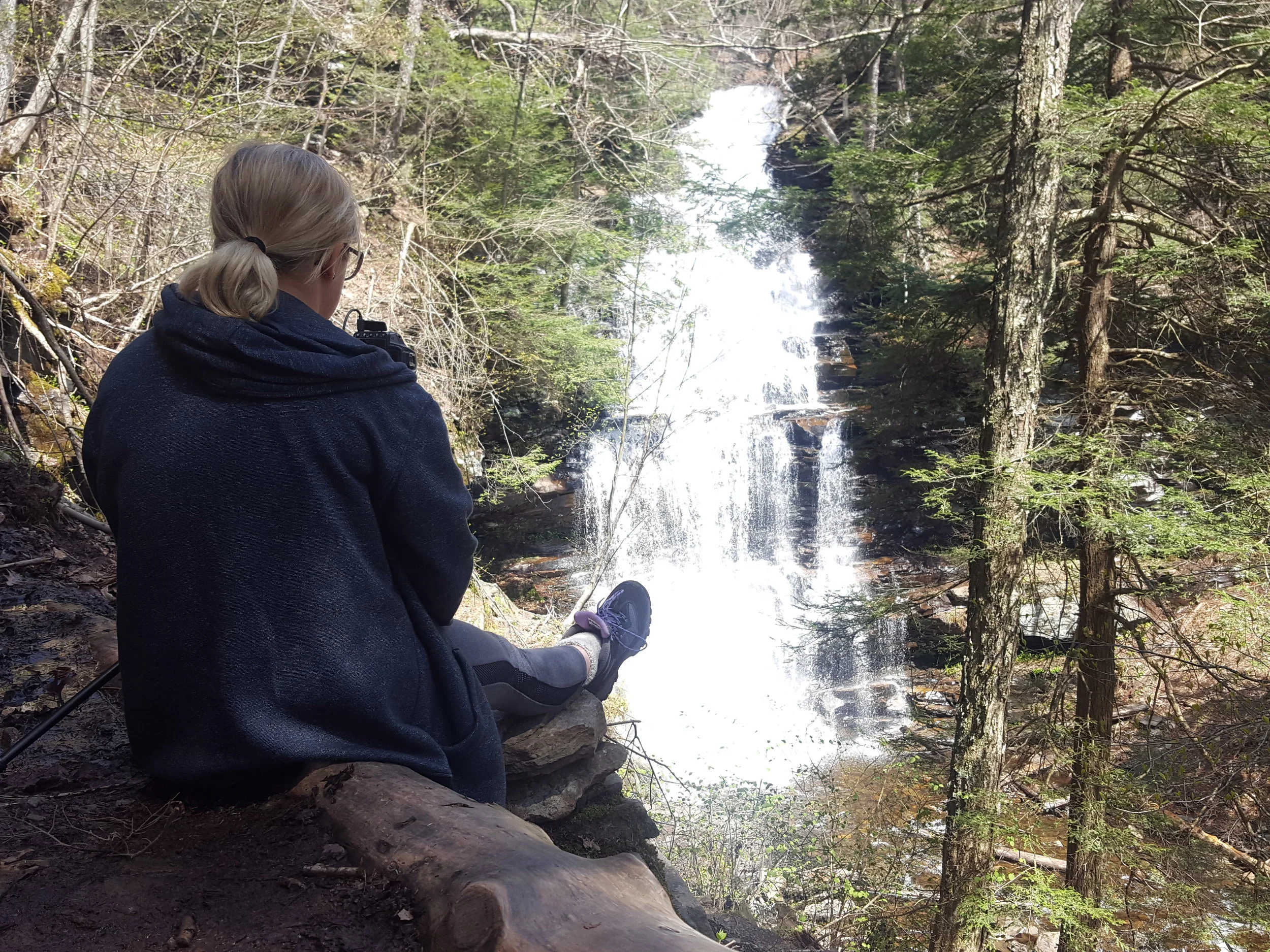 melanie relaxing in front of a waterfall as she does a long-exposure photograph of it