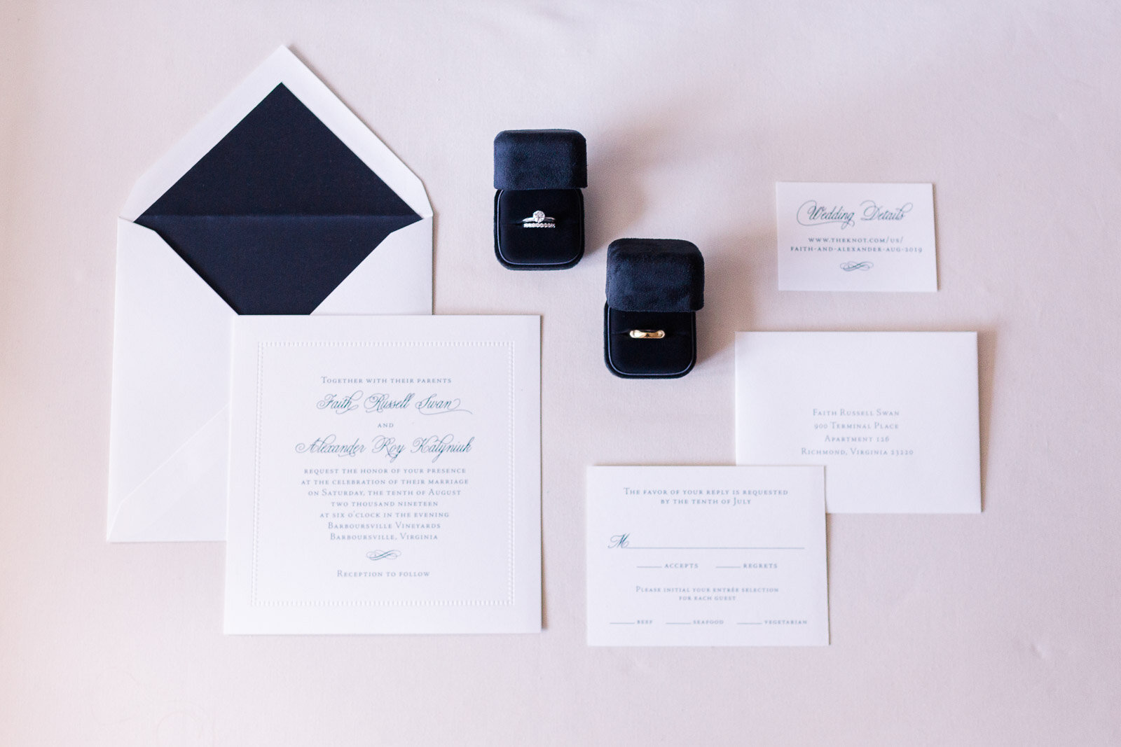 detail-shot-white-and-navy-wedding-invitation-suite-and-wedding-bands-on-flatlay