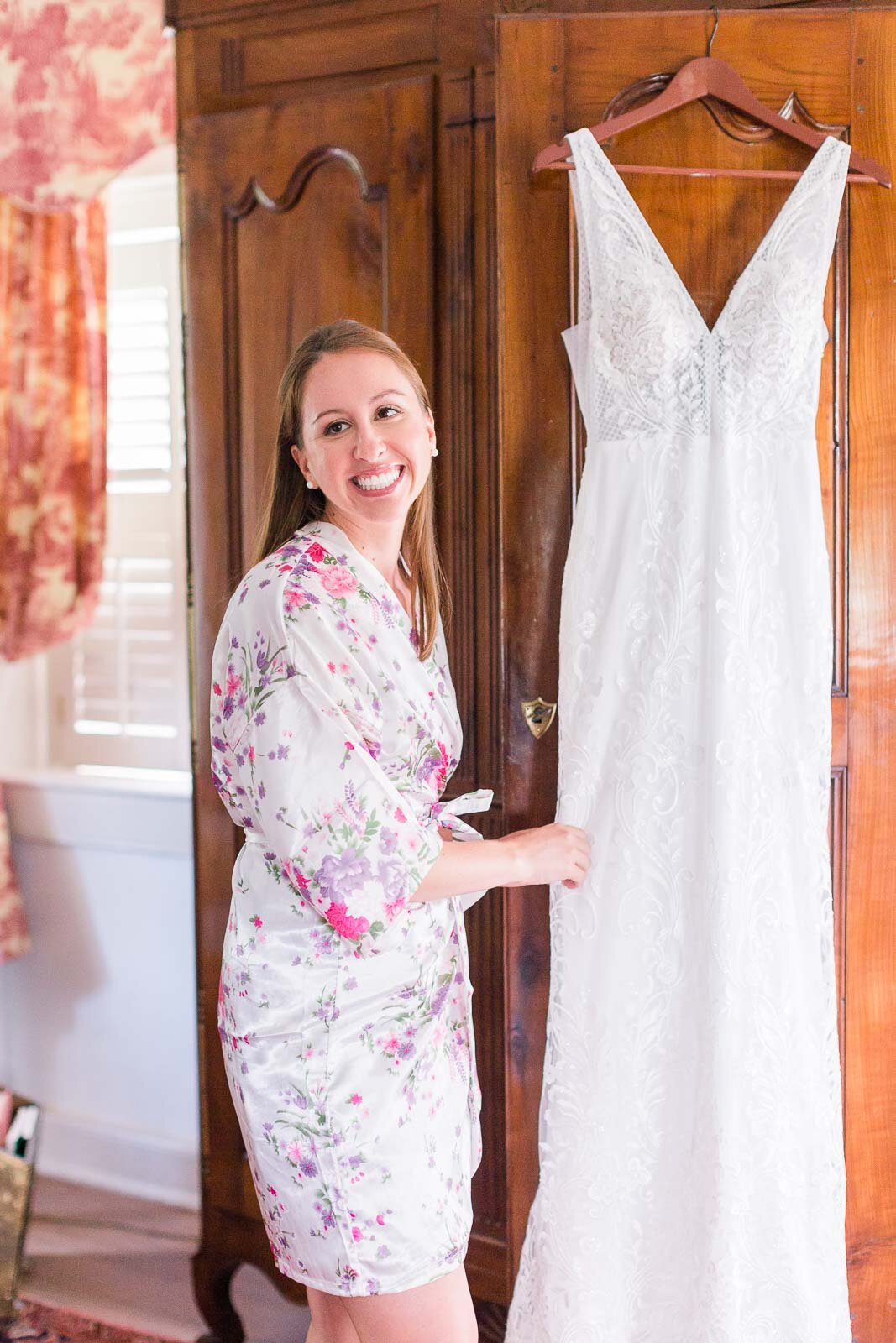 bride-touching-wedding-dress-as-it-hangs-up