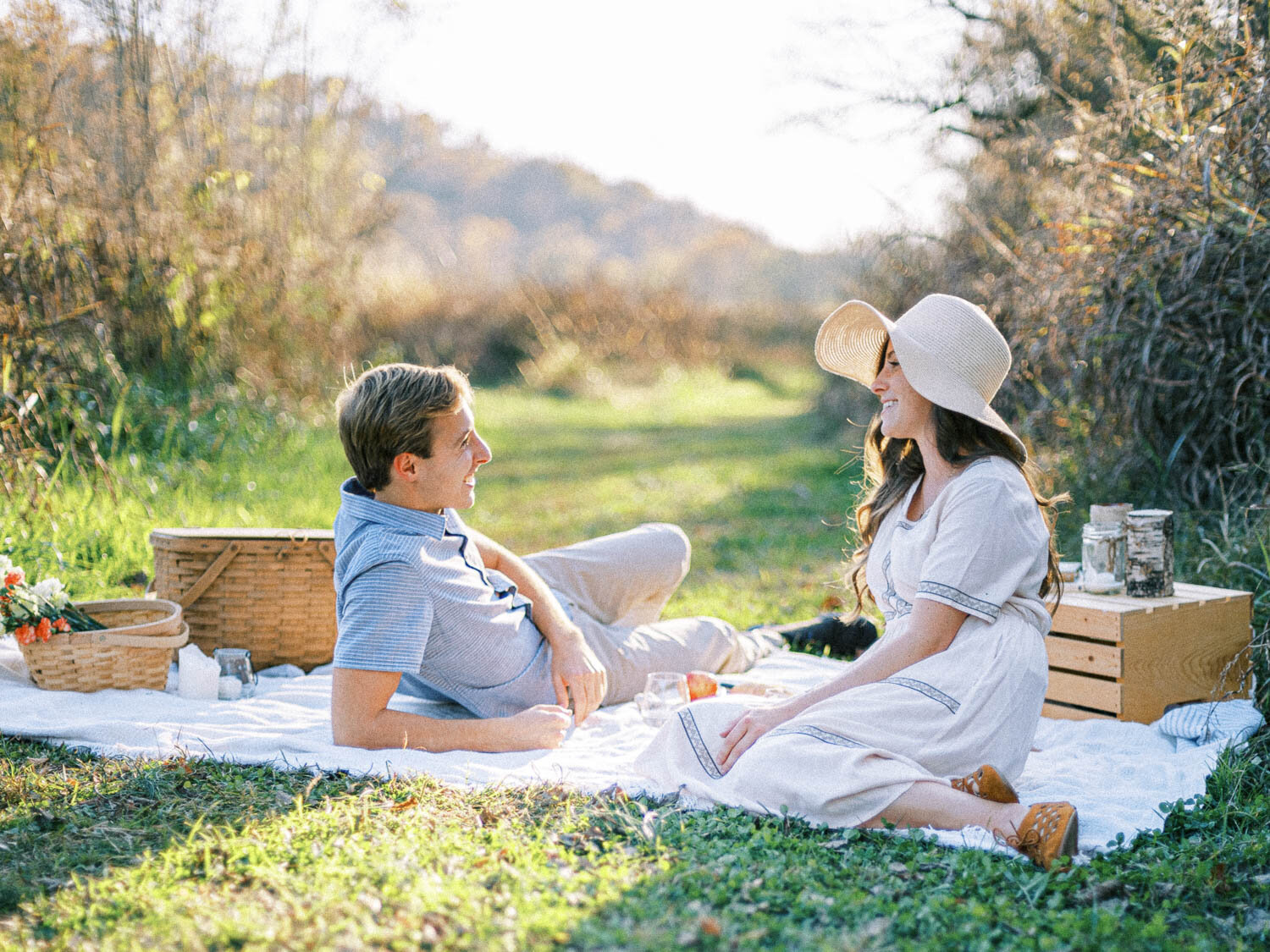 engaged-man-and-woman-lay-across-from-each-other-on-white-picnic-blanket-for-their-fall-engagement-session-in-virginia.jpg