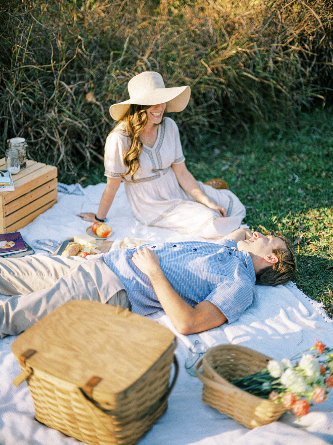 engaged-man-and-woman-sit-across-from-each-other-on-white-picnic-blanket-for-their-fall-engagement-session-in-virginia.jpg