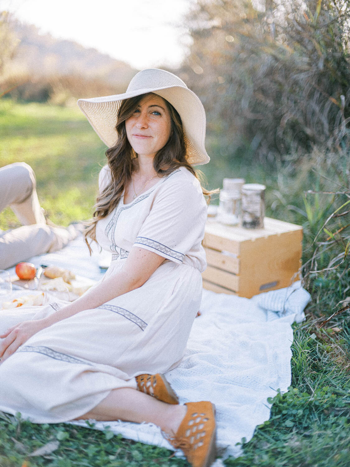woman-in-straw-hat-looks-at-camera-during-her-romantic-engagement-session-picnic-in-charlottesville-virginia.jpg