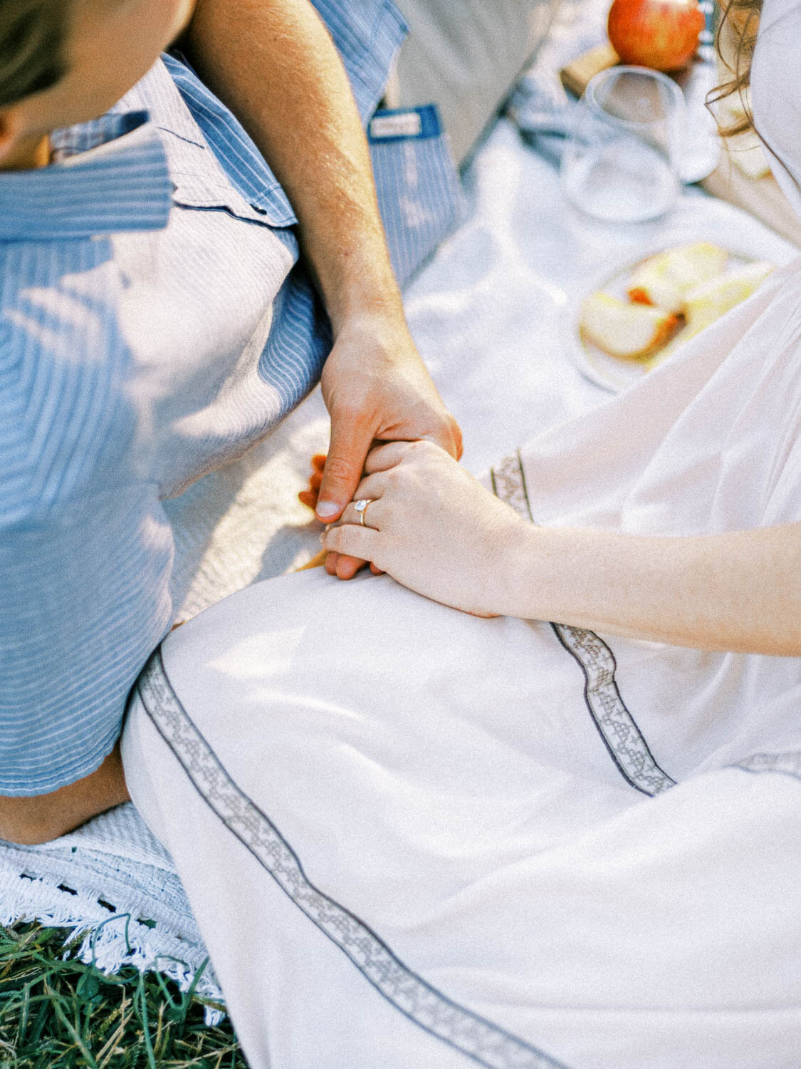man-and-woman-with-engagement-ring-hold-hands-during-fall-picnic-in-charlottesville-virginia.jpg