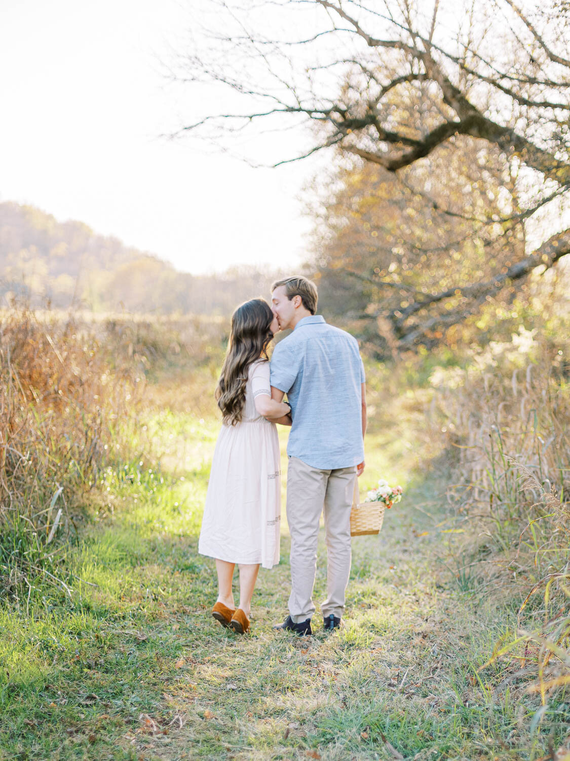 woman-kisses-her-fiance-on-the-lips-as-they-walk-down-a-path-during-their-fall-engagement-session-in-virginia.jpg