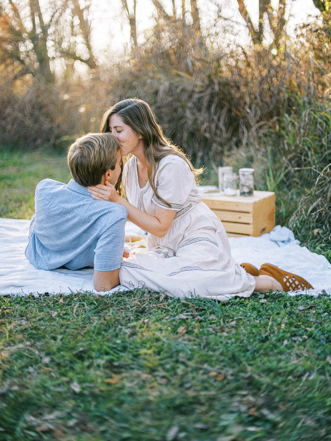 woman-kisses-her-fiance-on-the-forehead-as-he-lays-down-on-picnic-blanket-during-their-fall-engagement-session-in-charlottesville-virginia.jpg