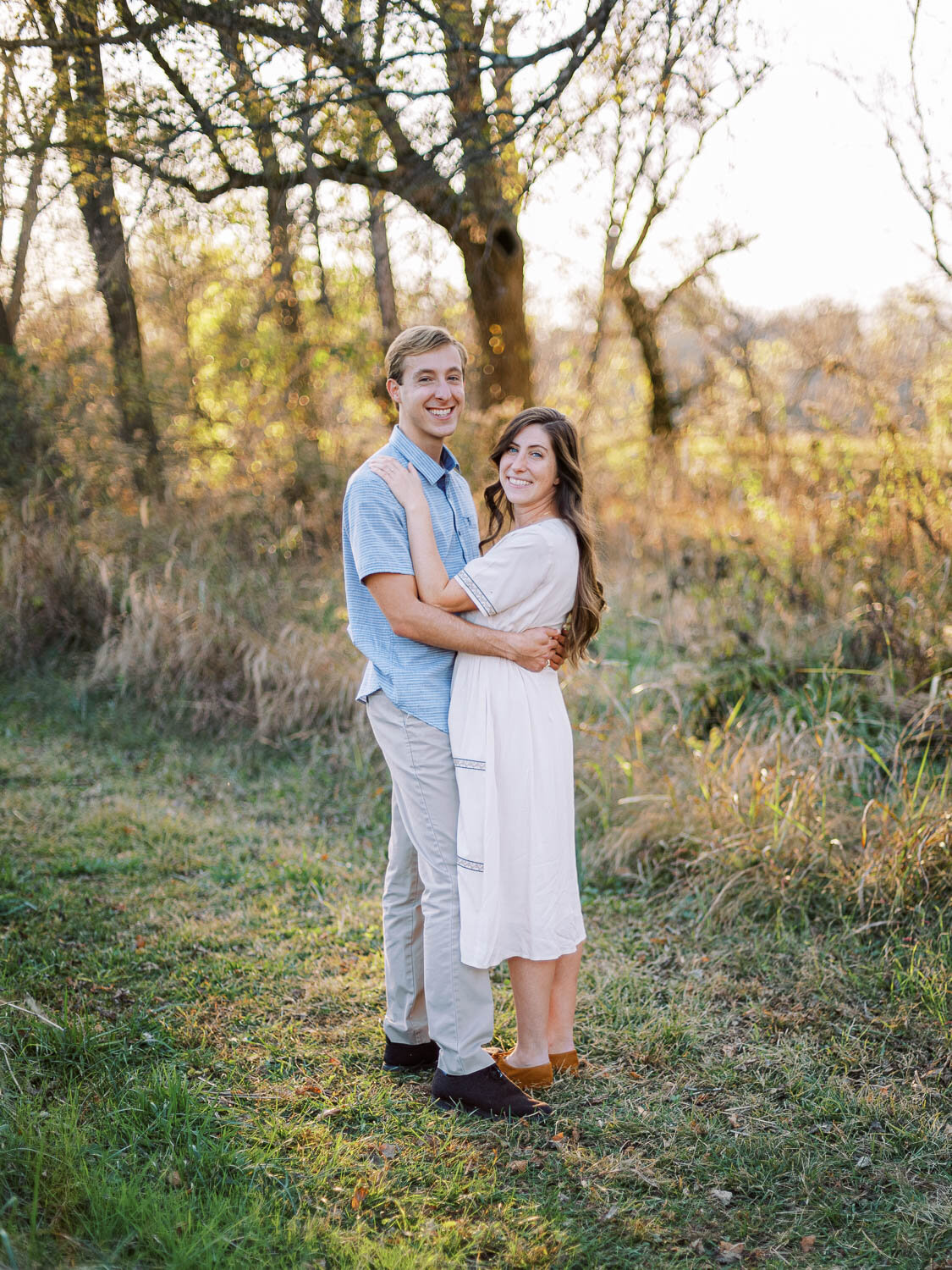 man-and-woman-smile-at-camera-and-hold-each-other-close-as-they-pose-for-their-fall-engagement-session.jpg