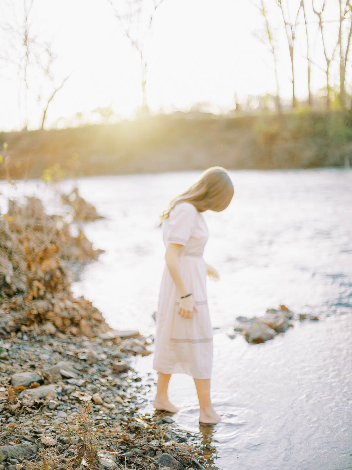 woman-wading-into-rivanna-river-during-fall-engagement-session-at-golden-hour-in-charlottesville-virginia.jpg