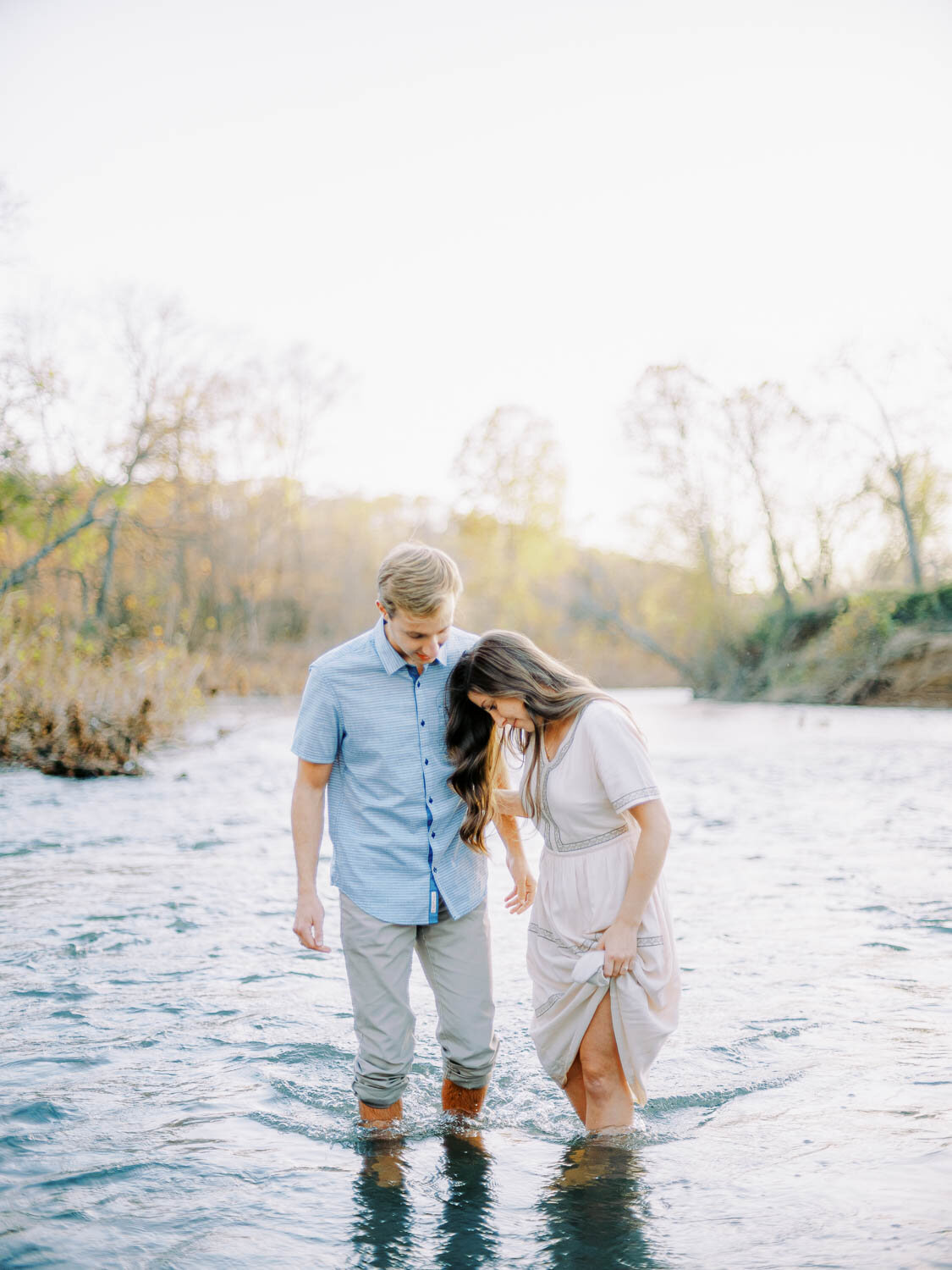 man-and-woman-holding-each-other-and-standing-in-rivanna-river-during-fall-engagement-session-at-golden-hour-in-charlottesville-virginia.jpg