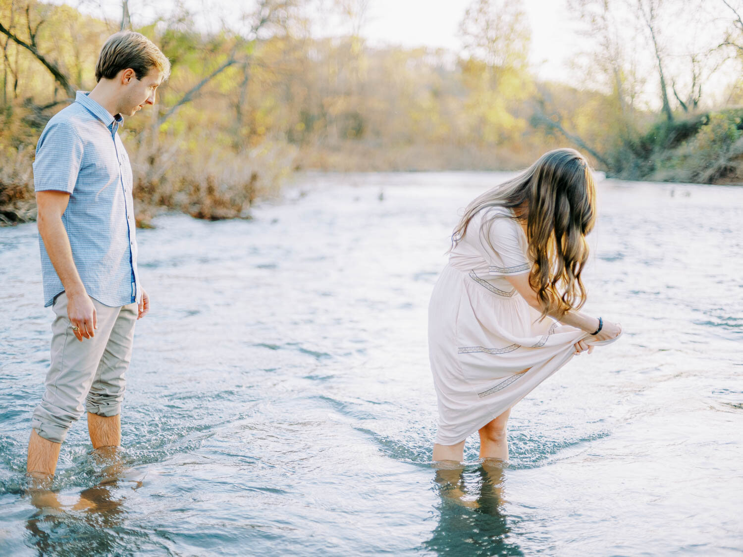 man-and-woman-wading-into-rivanna-river-during-fall-engagement-session-at-golden-hour-in-charlottesville-virginia.jpg