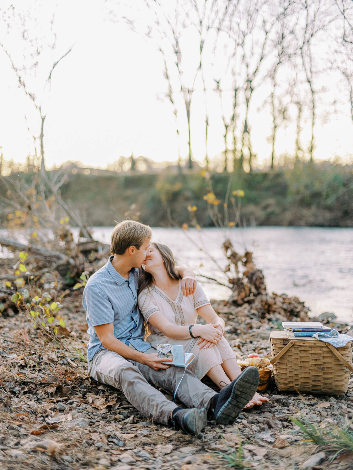 man-and-woman-barely-kissing-while-sitting-side-by-side-on-riverbank-during-engagement-session-in-charlottesville-virginia.jpg