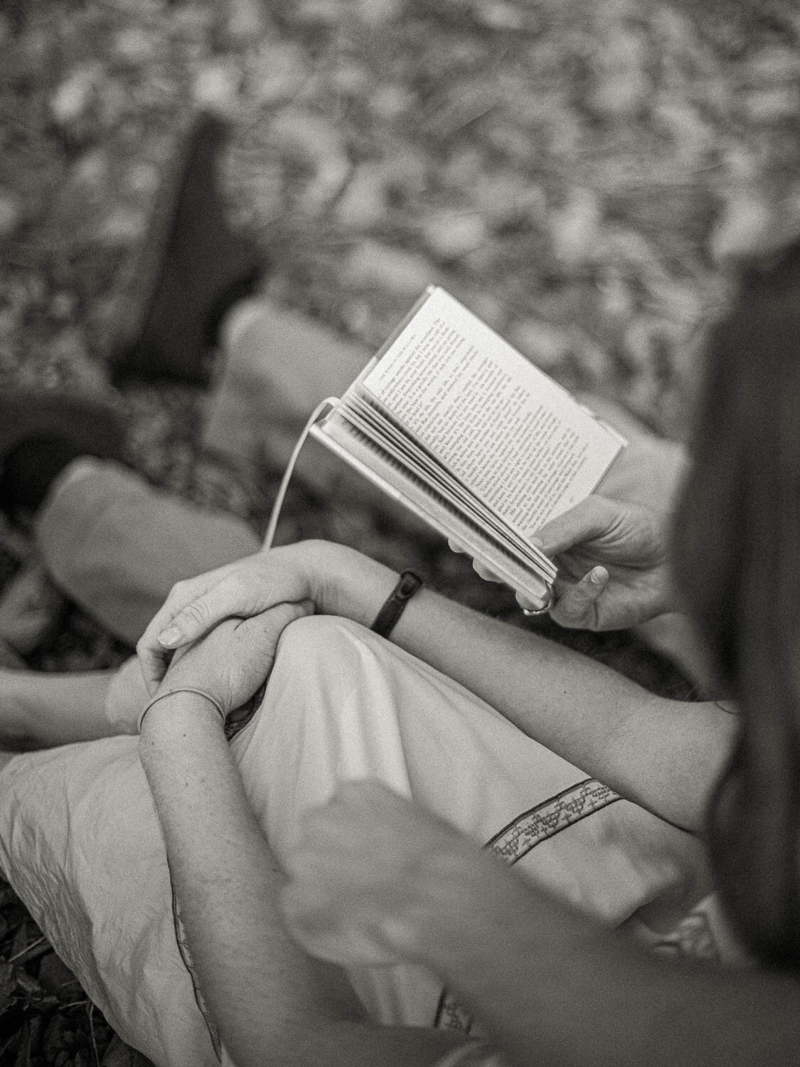 man-and-woman-sitting-side-by-side-reading-book-on-riverbank-during-engagement-session-in-charlottesville-virginia.jpg