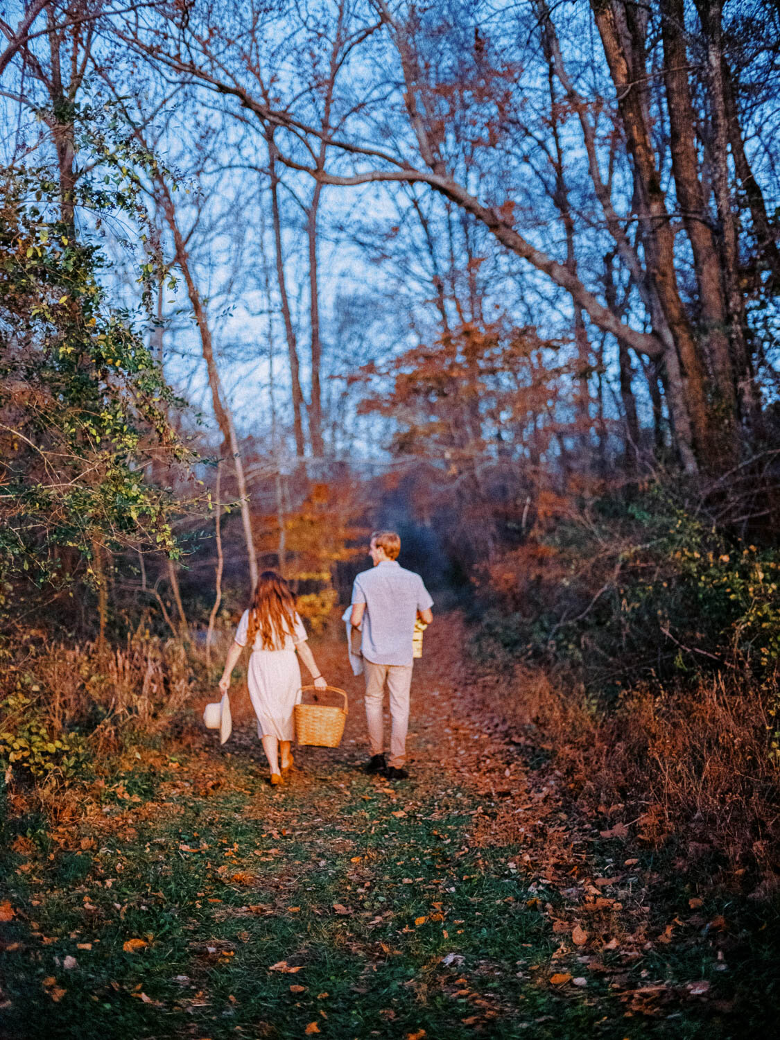 man-and-woman-walk-into-woods-at-sunset-during-charlottesville-fall-engagement-session.jpg