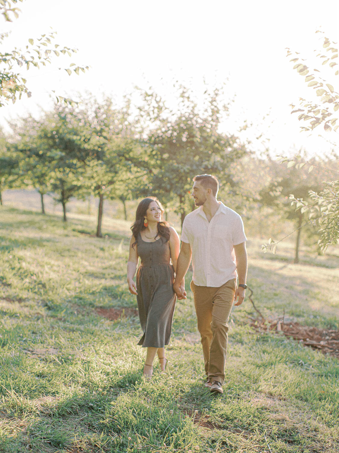 engaged-couple-holding-hands-and-walking-on-hillside-at-market-at-grelen-charlottesville.jpg