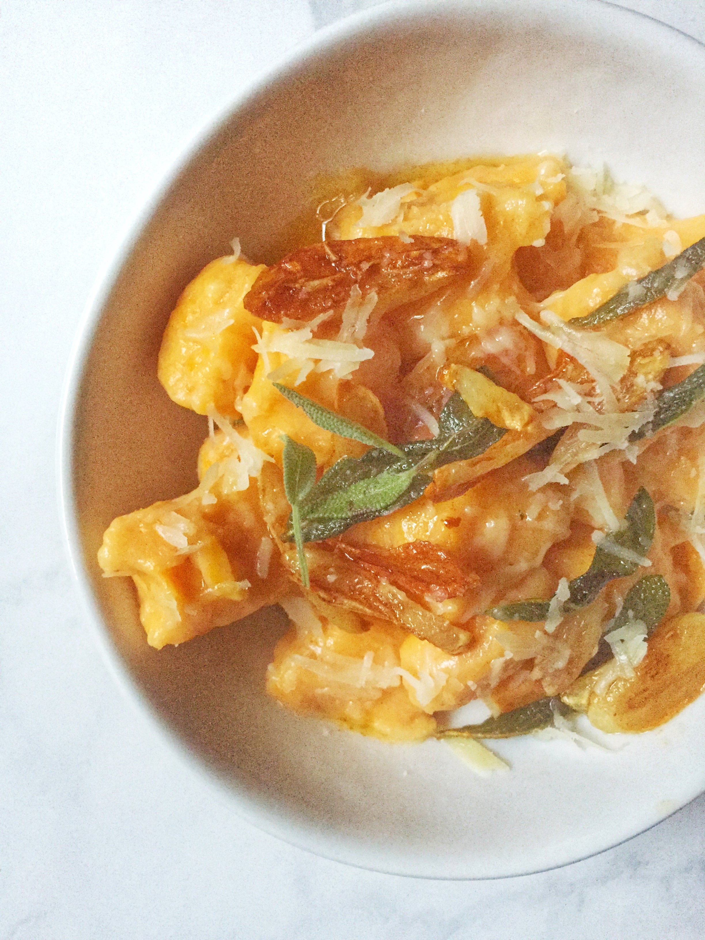 sweet potato & ricotta gnocchi with garlic & brown butter sauce garnished with parmesan cheese & crispy sage leaves