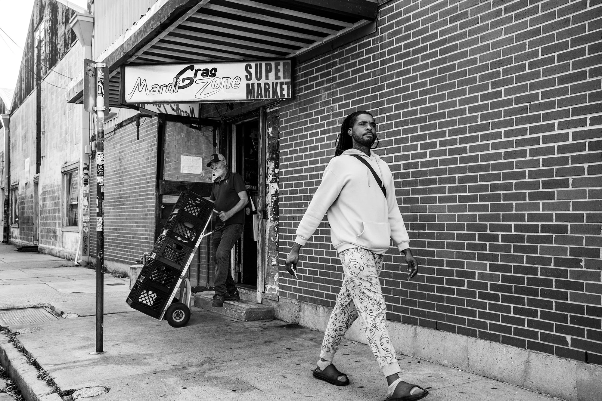 Man walking by the Mardi Gras Zone Super Market, Bywater, New Orleans, Louisiana, USA