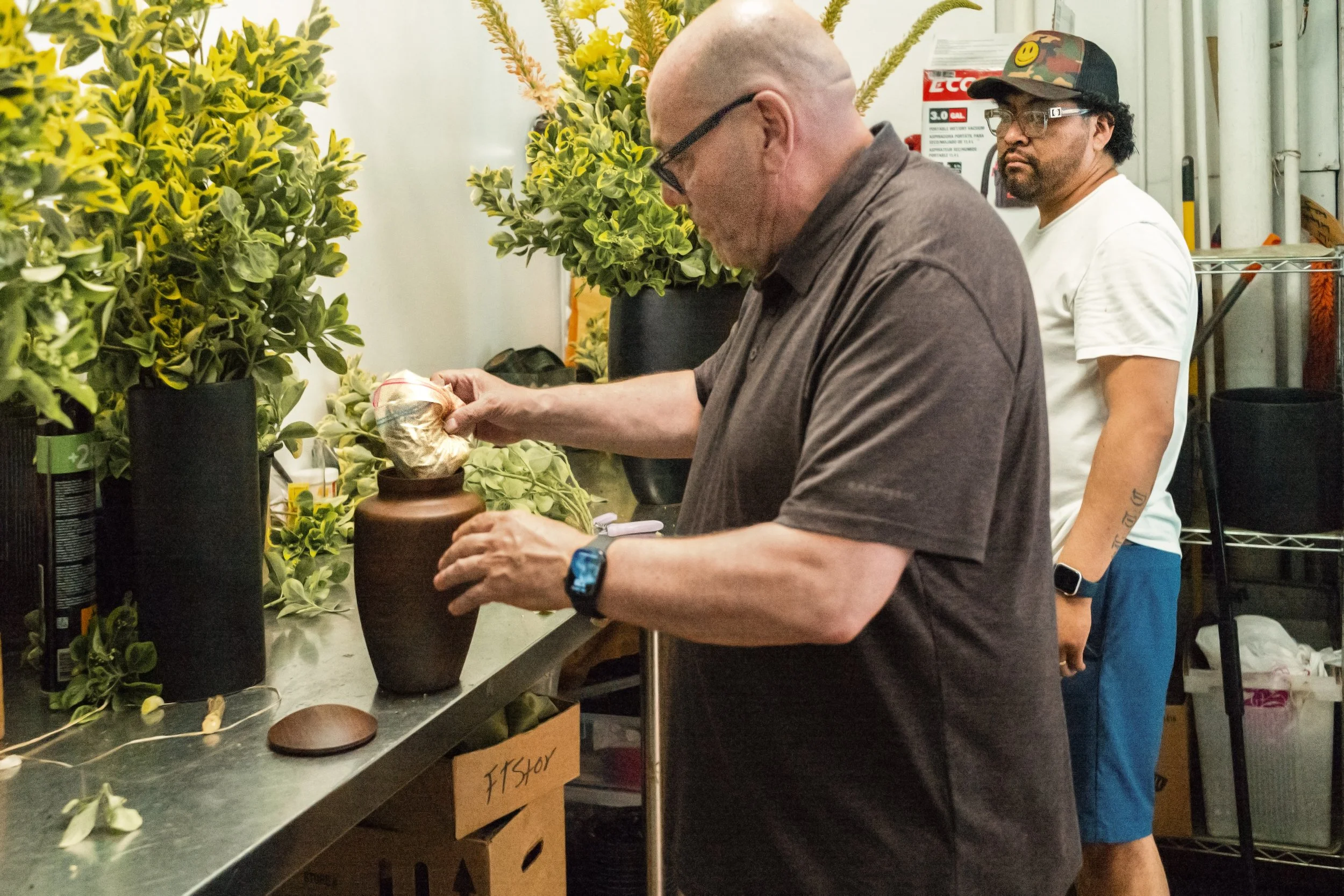 A flower shop employee watches as Mikey Flowers places the ashes and dust he collected in the urn that I gifted to him