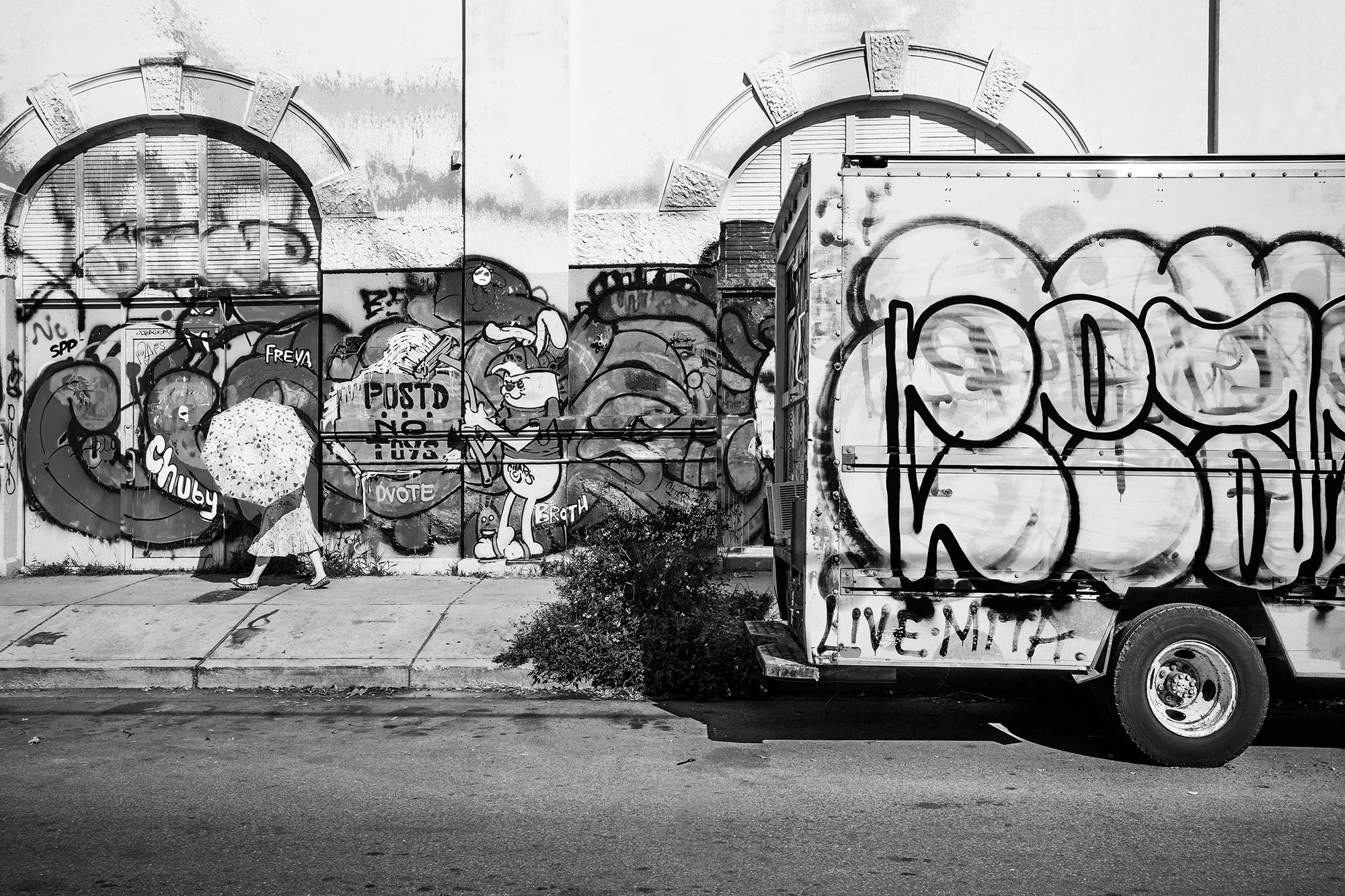 Lady with an umbrella walking in front of graffiti, Marigny, New Orleans, Louisiana, USA