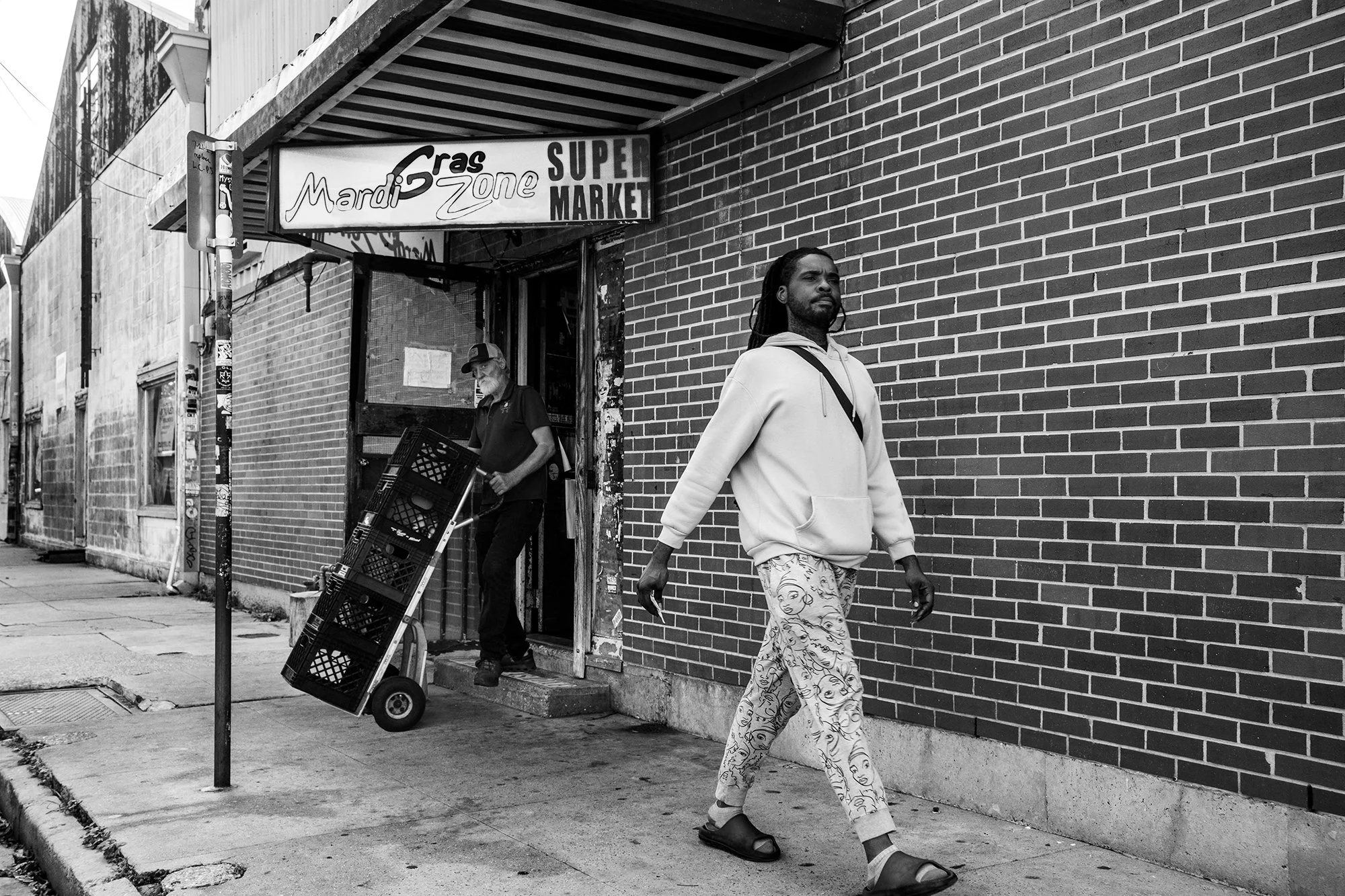 Man walking by the Mardi Gras Zone Super Market, Bywater, New Orleans, Louisiana, USA
