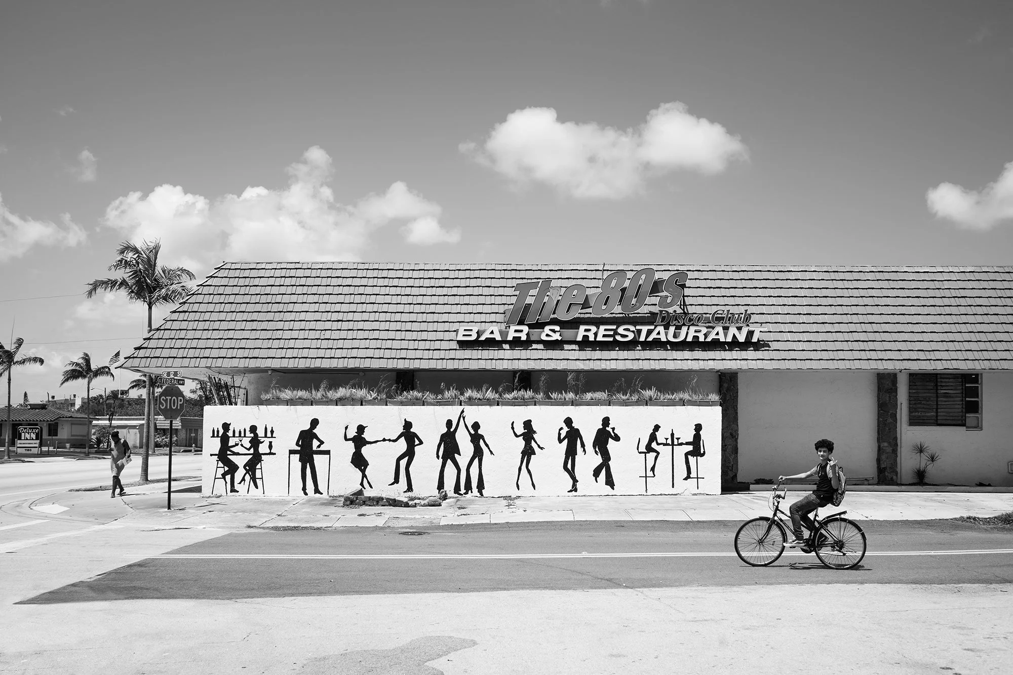 Boy on bicycle passing by The 80s Disco Club Bar & Restaurant, Dania Beach, Florida, USA