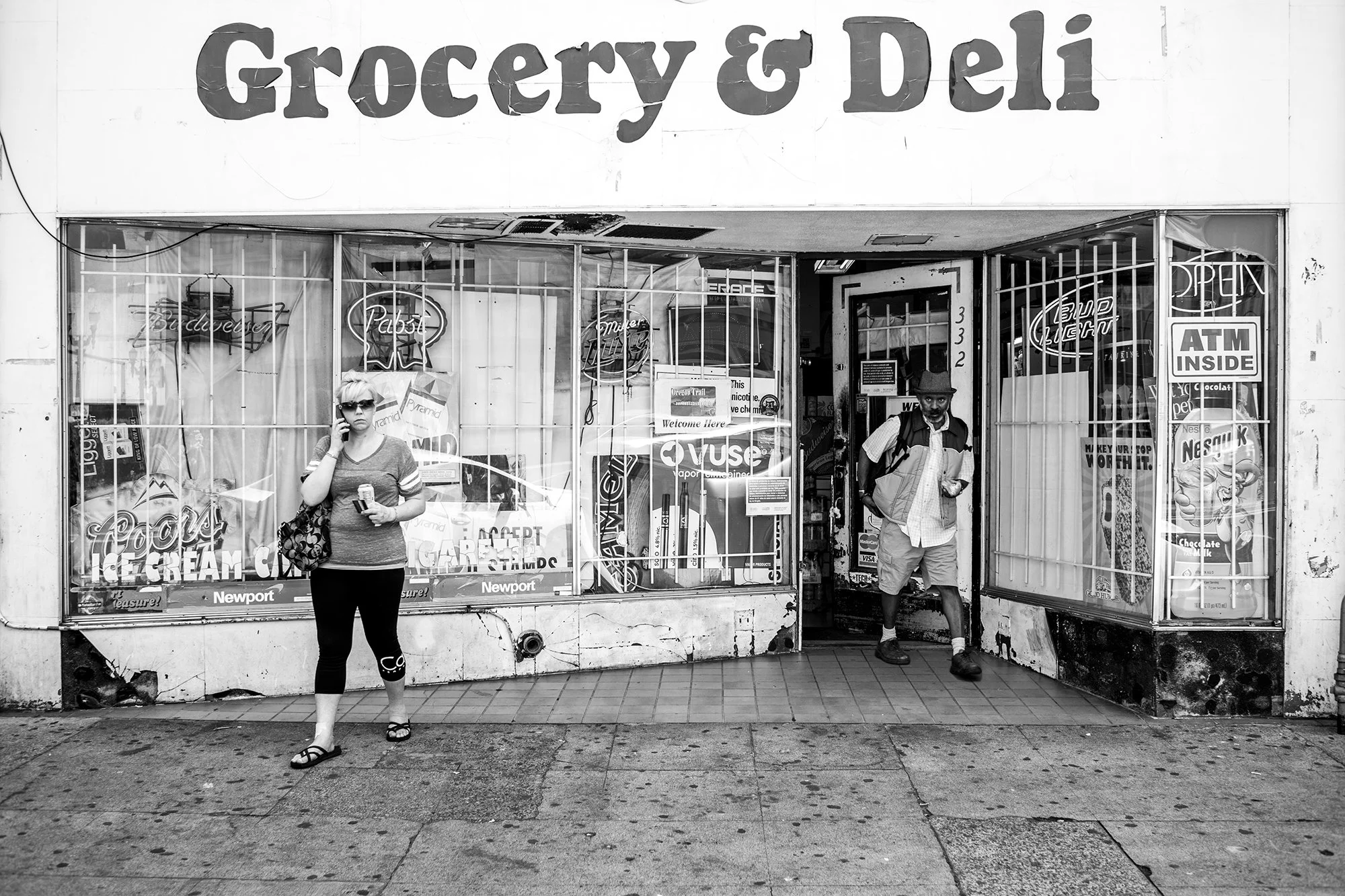 Lady on the phone and man coming out of Grocery and Deli Store in Portland, Oregon, USA