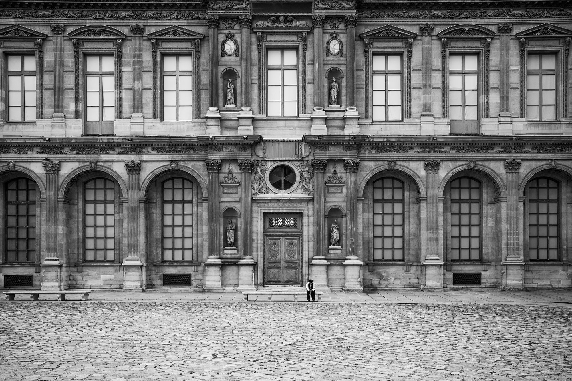 Man sitting alone in front of the Louvres Museum, Paris, France