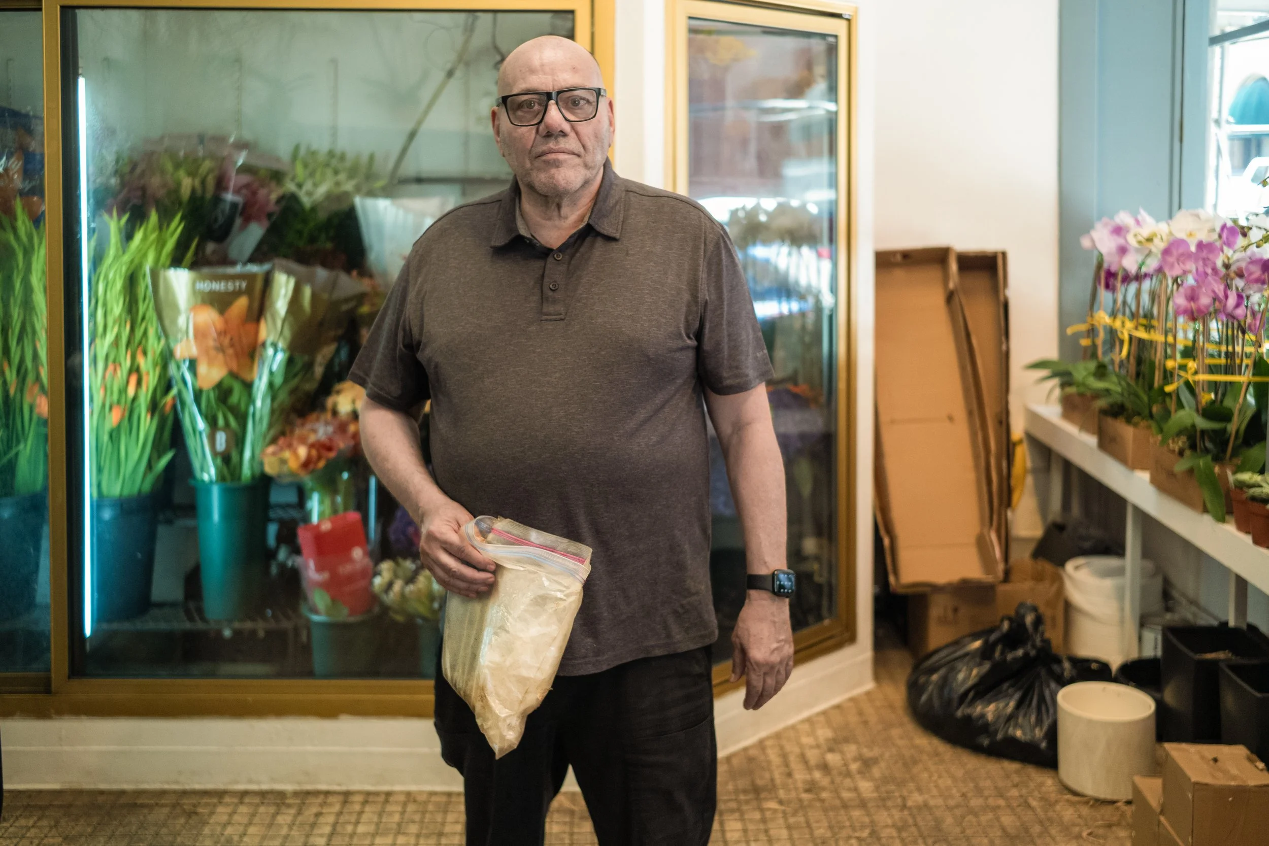 Mikey Flowers shows the ashes and dust that he collected from his clothes each day when returning home from Ground Zero.He put those in a resealable plastic bag that he keeps in the floral coolers seen behind him on this photo.