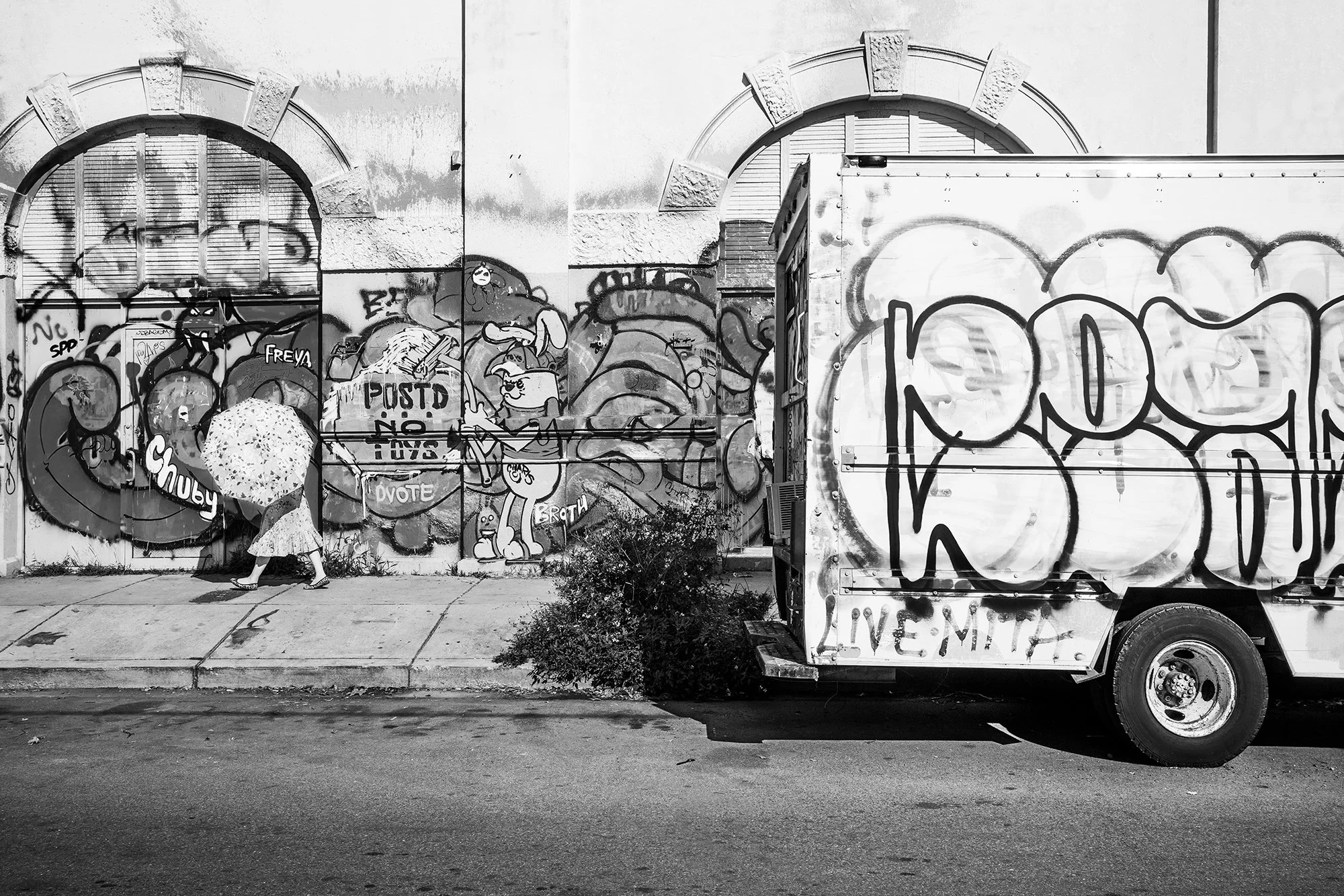 Lady with an umbrella walking in front of graffiti, Marigny, New Orleans, Louisiana, USA