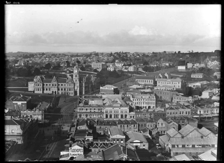 1906: Looking down Wellesley Street West towards Wellesley Street East showing Auckland Public Library with Albert Park behind, Princes Street left off Wellesley Street East with police station on corner of Princes and O'Rorke Streets, Park Hotel (centre right middle distance), YWCA (centre, middle distance), St Pauls Church, top right, Drill Hall, Tonson Garlick Company Limited (right), Abbots Opera House (bottom left) with business on Queen Street from Wellesley to Rutland Streets (Photo: Sir George Grey Special Collections, Auckland Libraries, 1-W19)