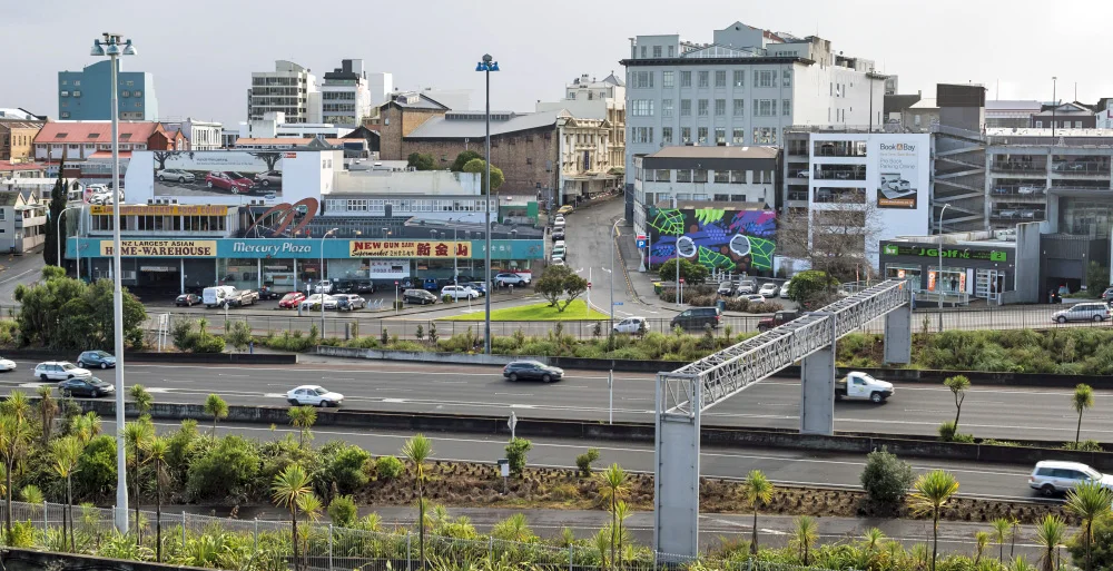 TODAY: Looking north from Ian McKinnon Drive across the Southern Motorway towards Canada Street (left to right, centre) and Mercury Lane (centre). The Mercury Plaza will be demolished so that construction vehicles and equipment could be placed there. After CRL is finished, a new development can be built there. (Photo: Sir George Grey Special Collections, Auckland Libraries, 1407-127)
