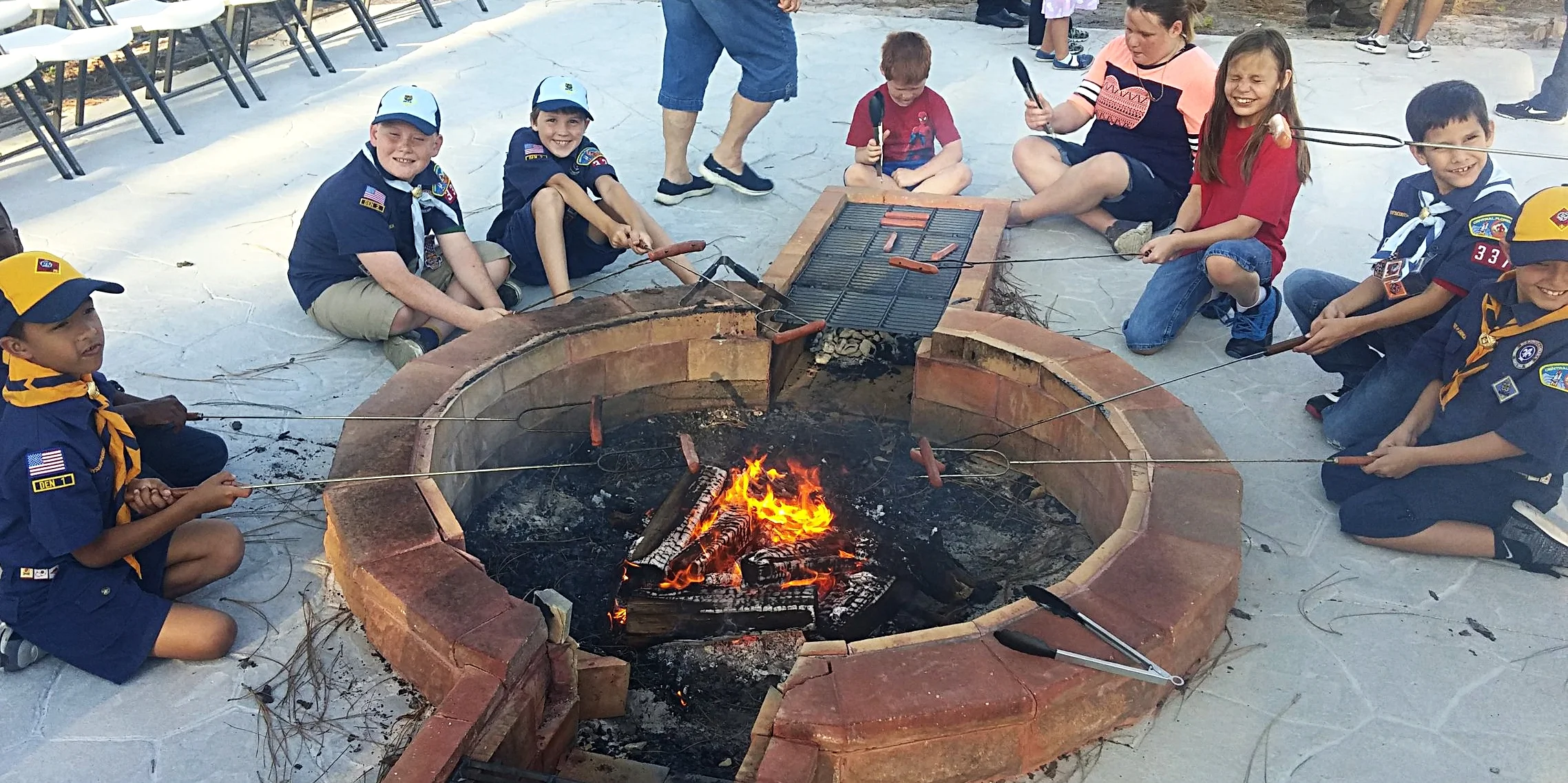 Cub&nbsp; Scouts &amp; Families from Pack 337 cooking hot dogs on the built-in grill Zachary designed and on skewers!