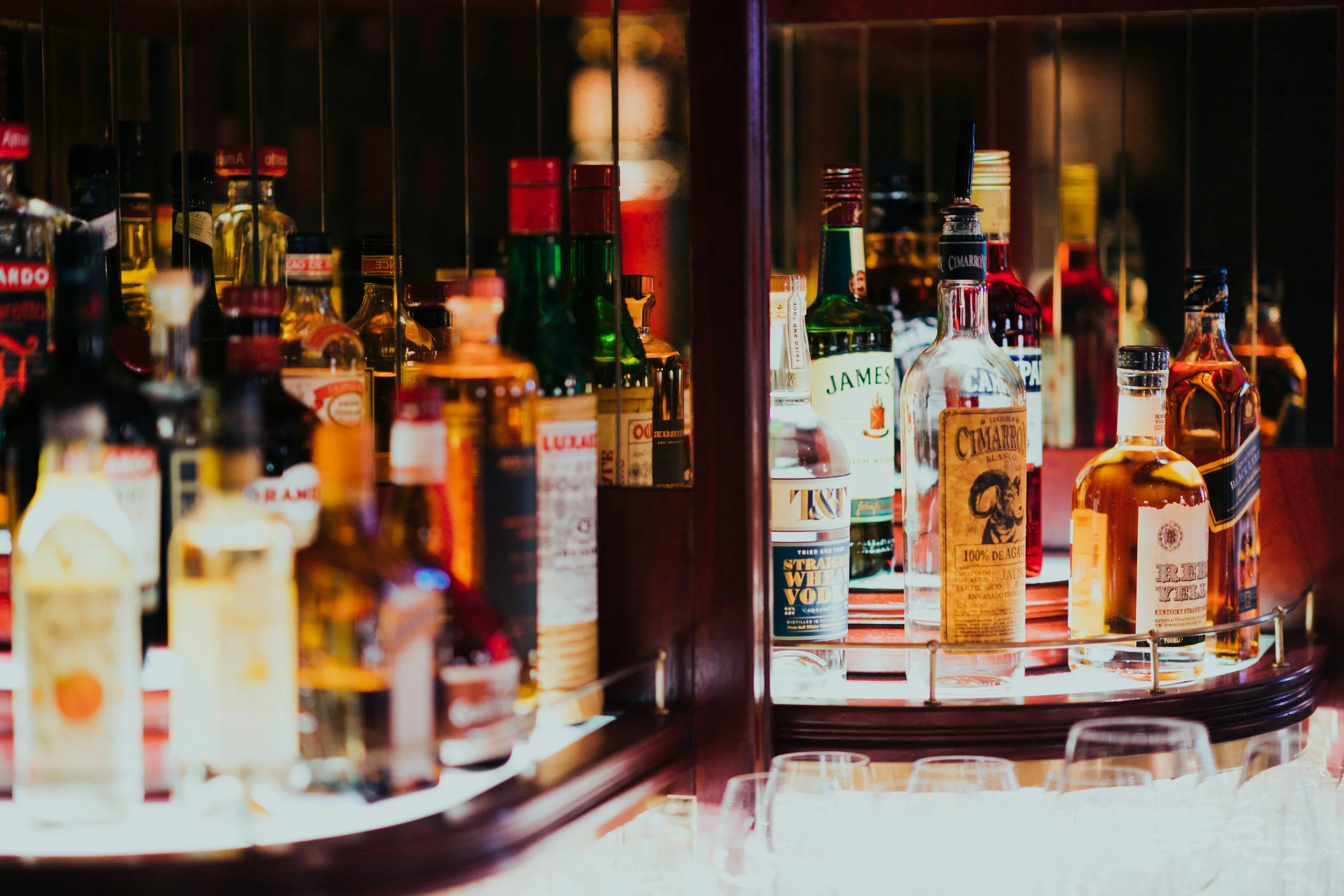 A bar shelf filled with various bottles of alcohol, including whiskey, tequila, and spirits.