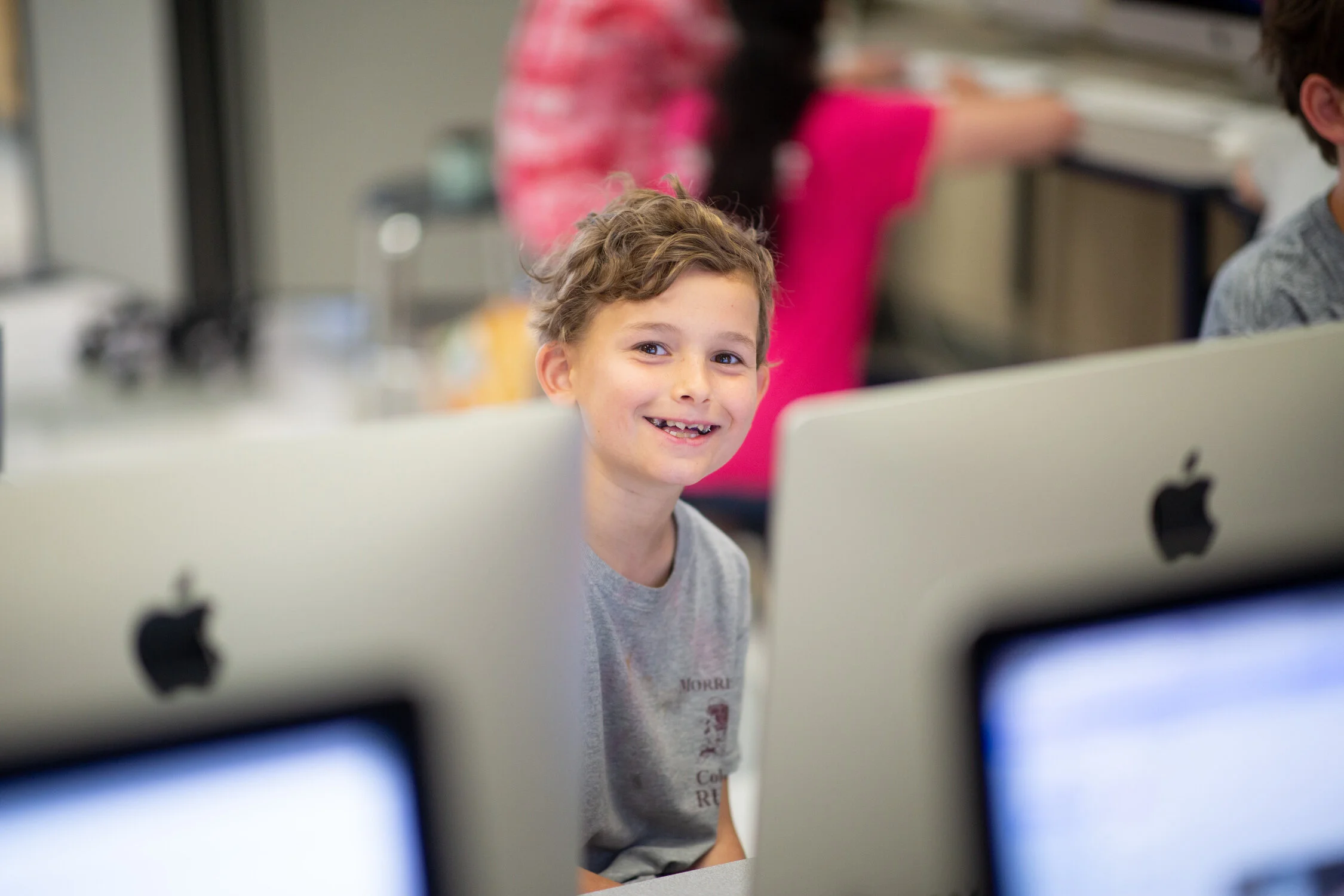 A student smiles while working in a computer class.