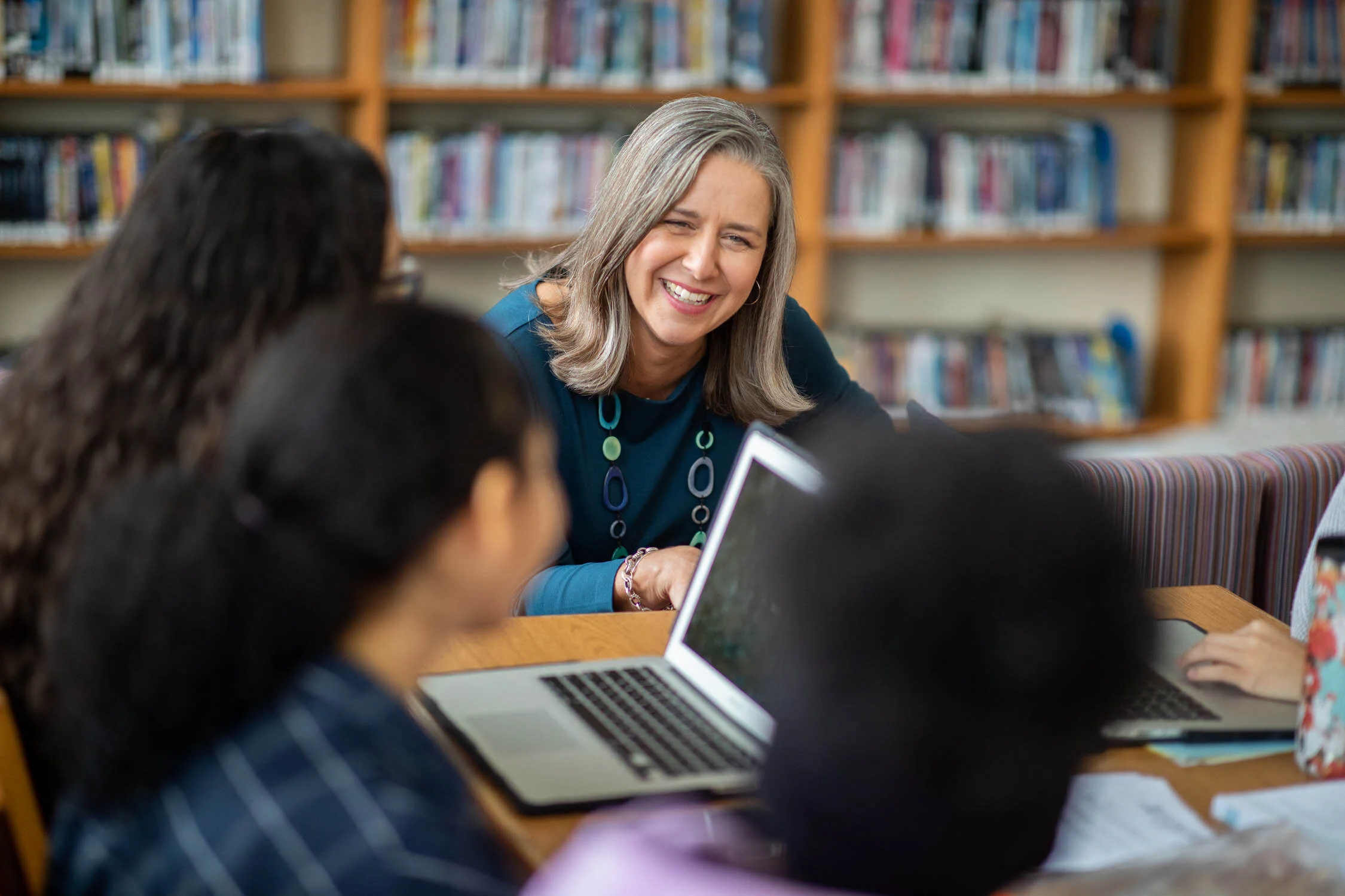 A teacher talks to students in a school library.