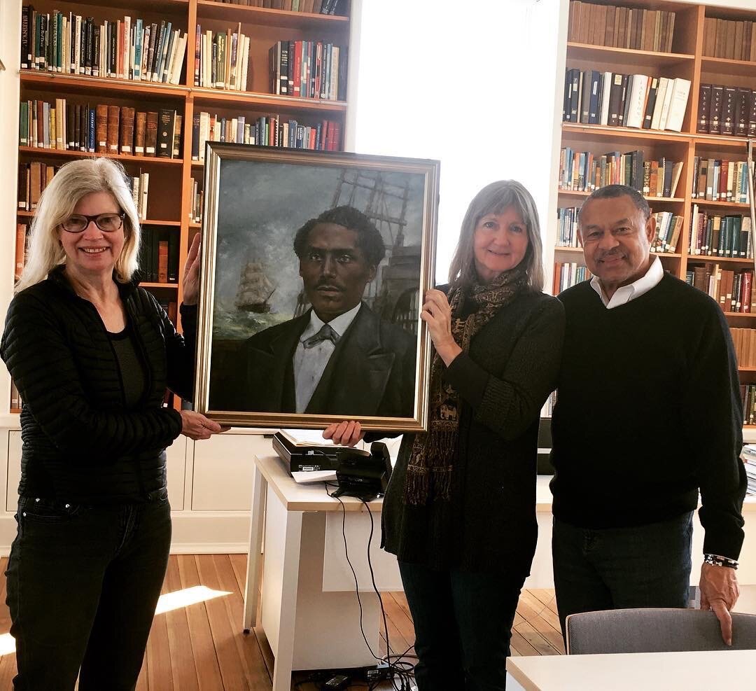  Martha’s Vineyard Museum Curator Bonnie Stacy receiving a gift of a painting of Captain Joseph Belain from artist Elizabeth Whelan and Skip Finley. 