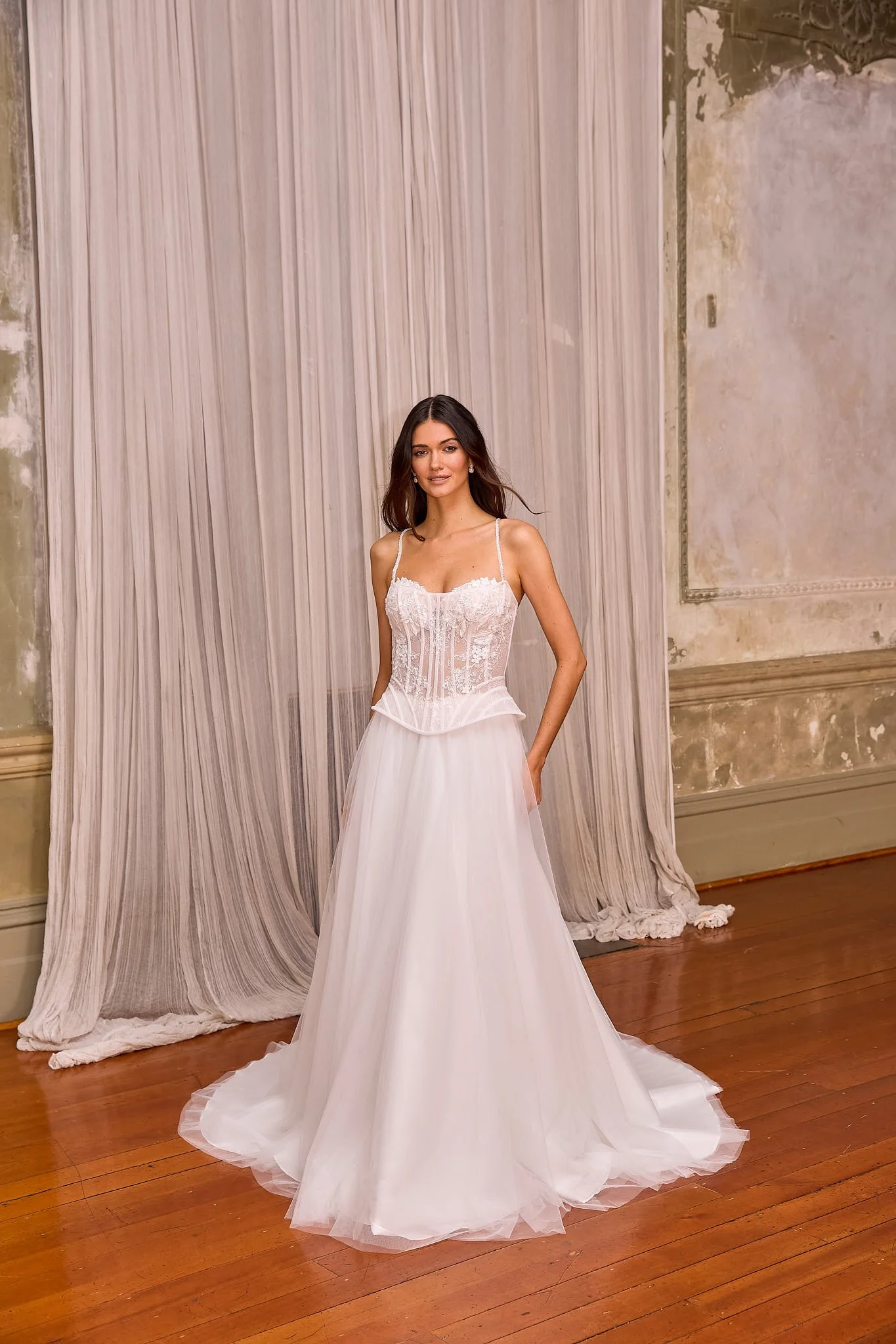 a romantic two-piece bridal gown featuring an exposed boning corset, lace appliqués, gathered tulle skirt and cathedral-length train.
