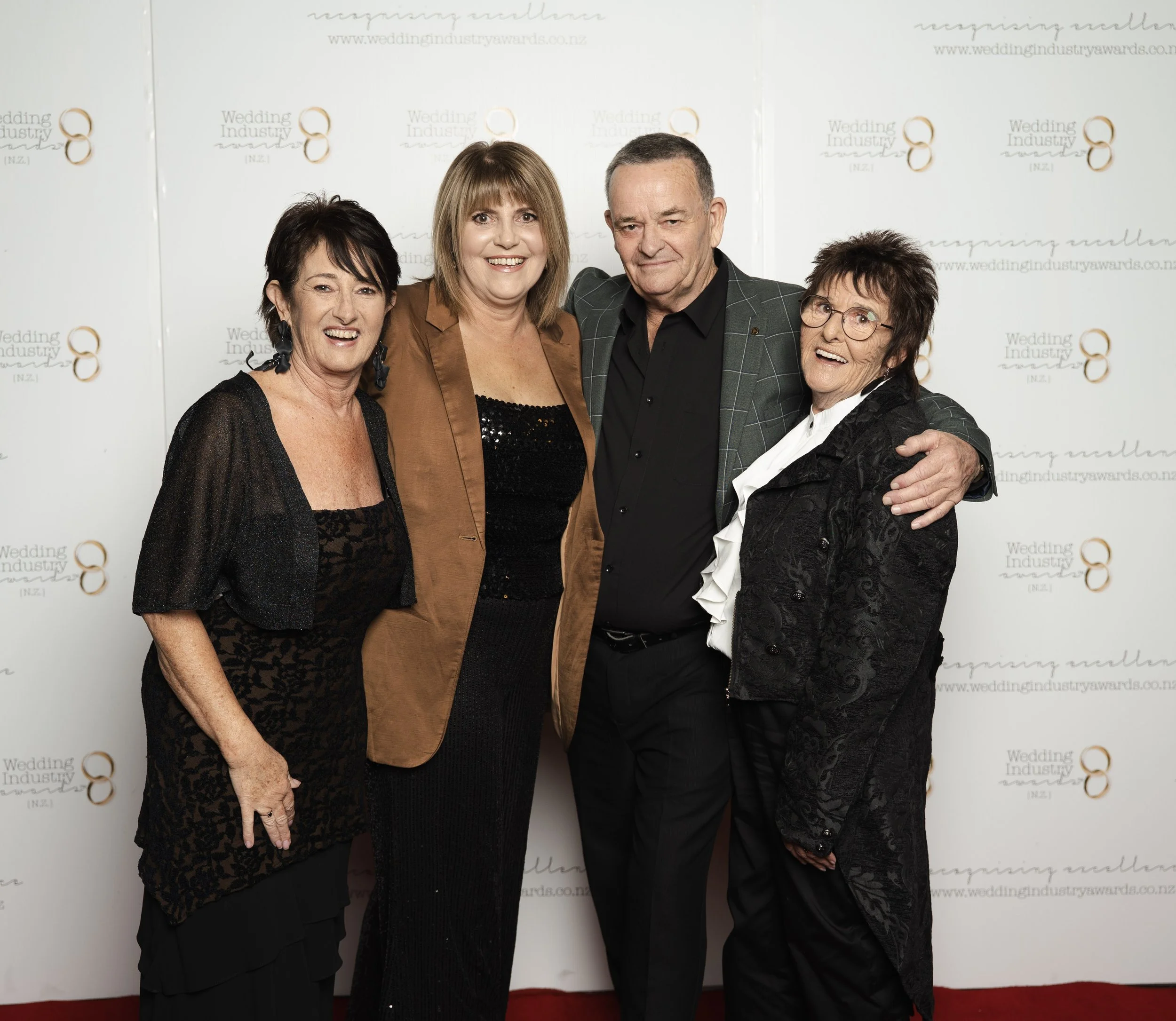 Four women and one man posing together at an awards event, standing in front of a backdrop with the text "Wedding Industry Awards" and logos.