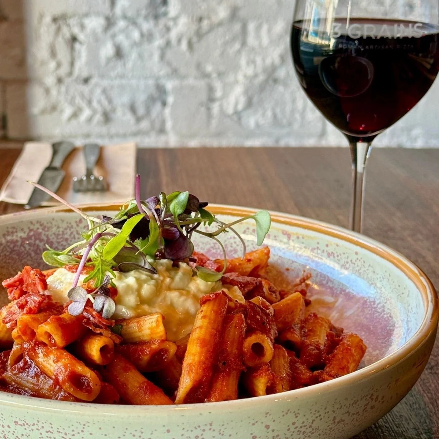 A plate of pasta with red wine on a table.