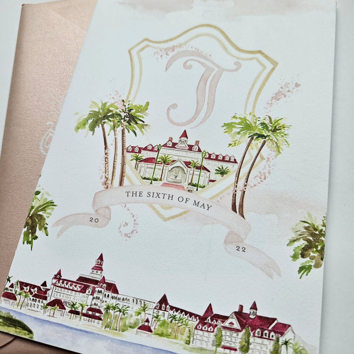 The front of a favorite gatefold by graphic designer @prettyinprintct for T&amp;J's wedding at Disney's Grand Floridian Resort +Spa, featuring the iconic venue watercolor and whimsical crest.  A sophisticated invitation suite complete with a custom m