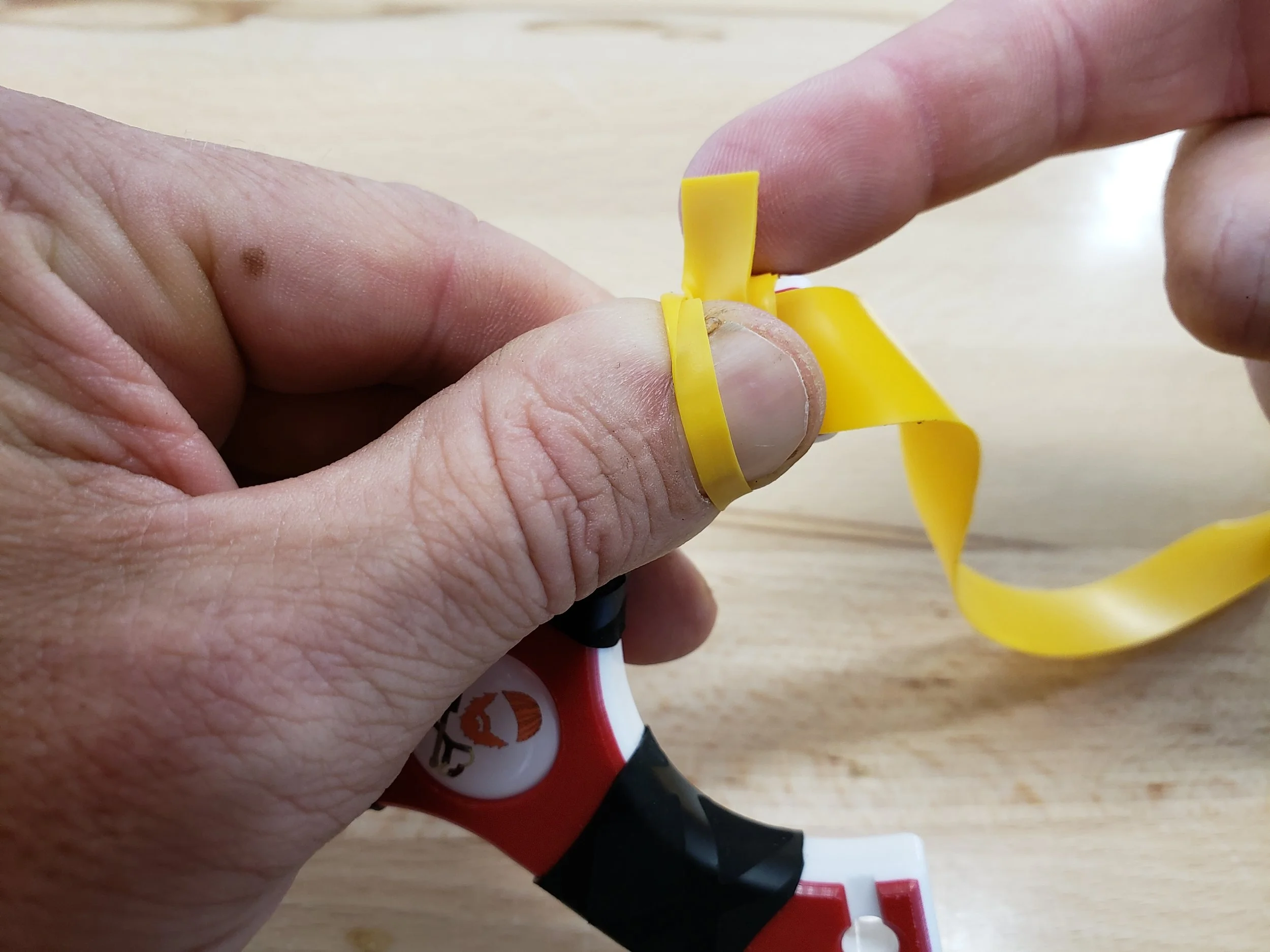 Step five: On the next wrap around, go underneath of your thumb and slowly pull the tie-on tail through the loop formed over your thumb