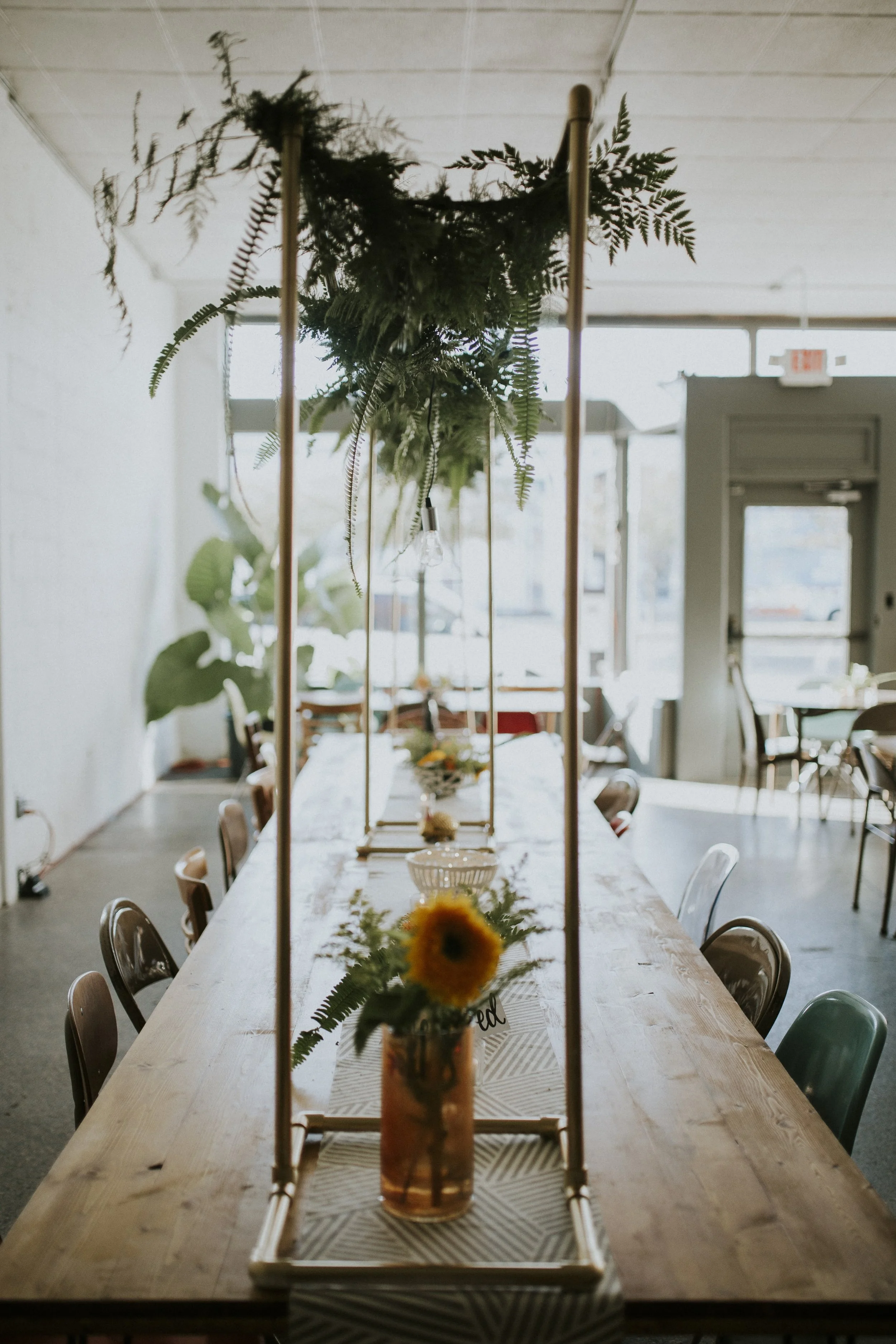 Modernly Events erected golden structures with draping greenery to add interest on the larger farmhouse tables. 